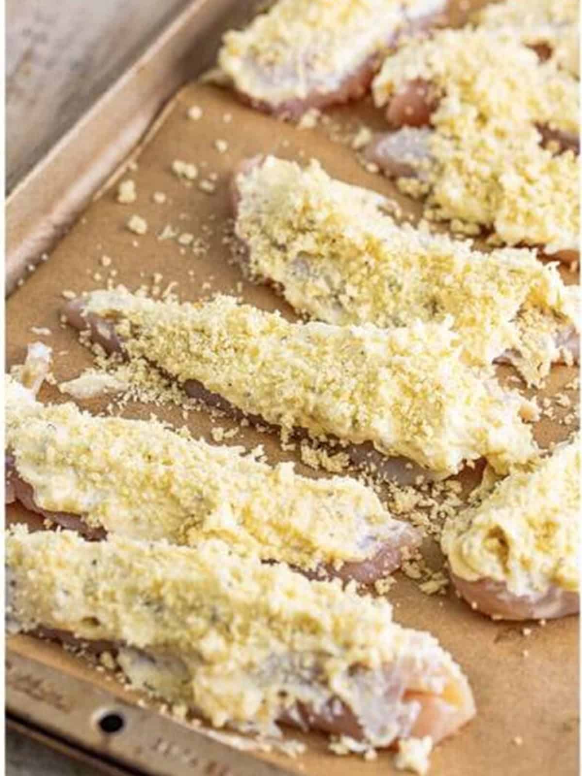 Panko breadcrumbs sprinkled over coated baked chicken tenders before baking.