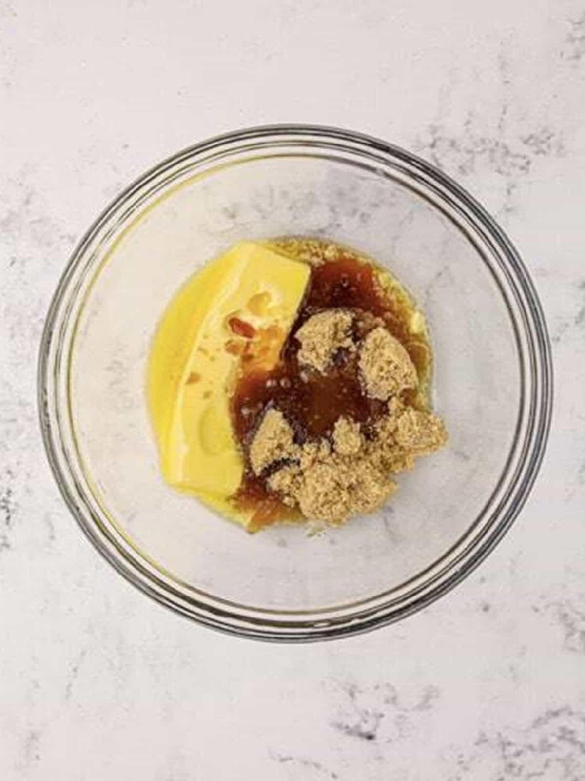 Melted butter, brown sugar, and vanilla creamed together in a glass bowl.
