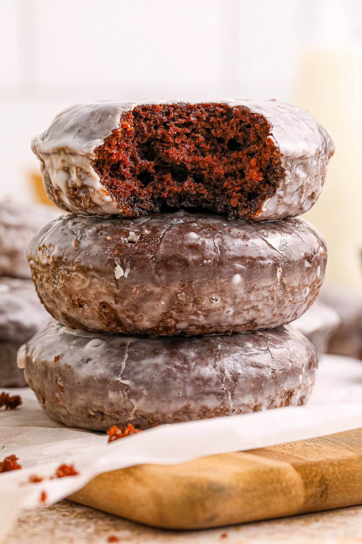 A glazed baked chocolate donut broken in half showing a moist chocolate cake interior.