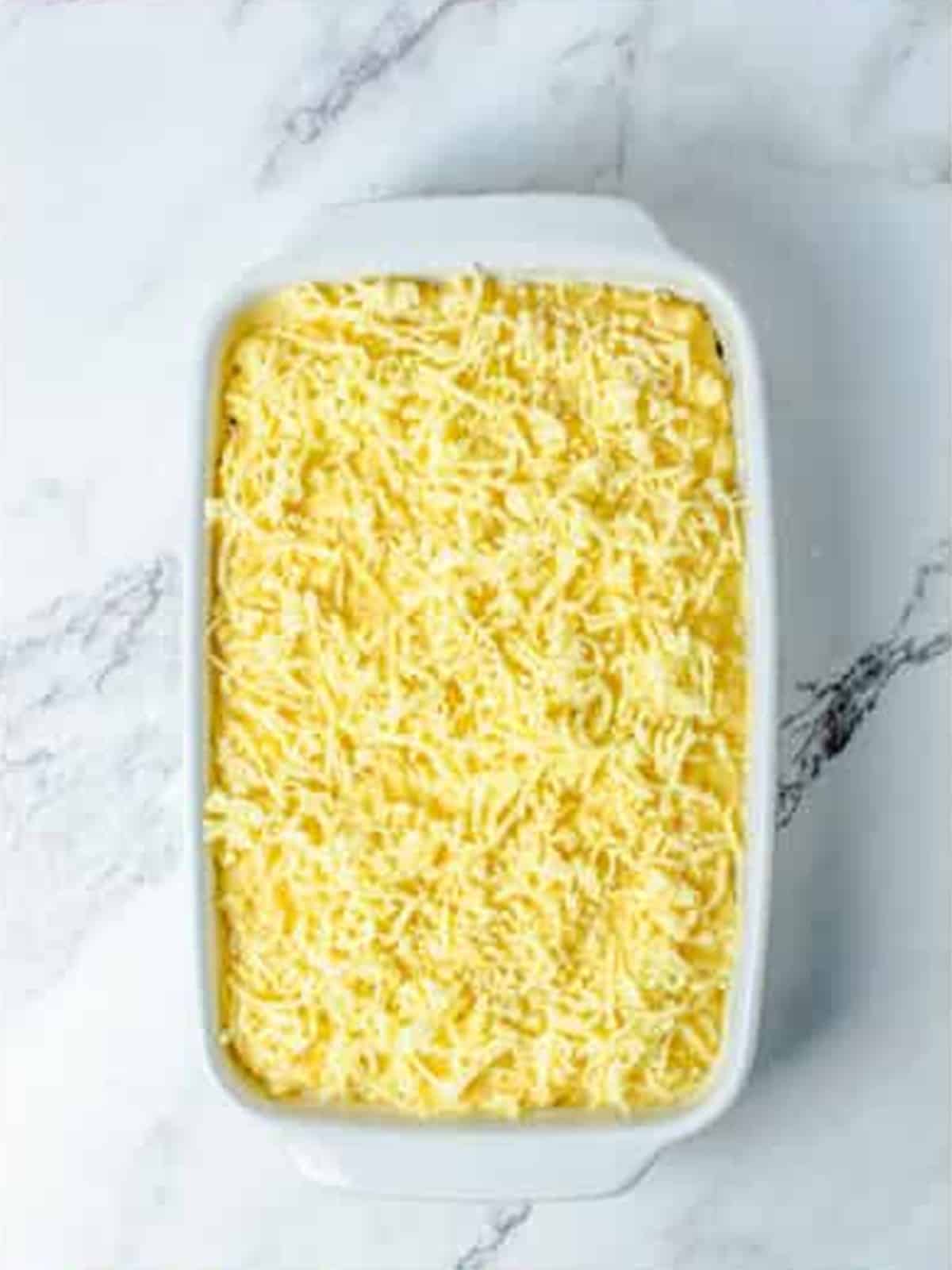 Macaroni tossed with cheese sauce in a baking dish and topped with more cheddar.