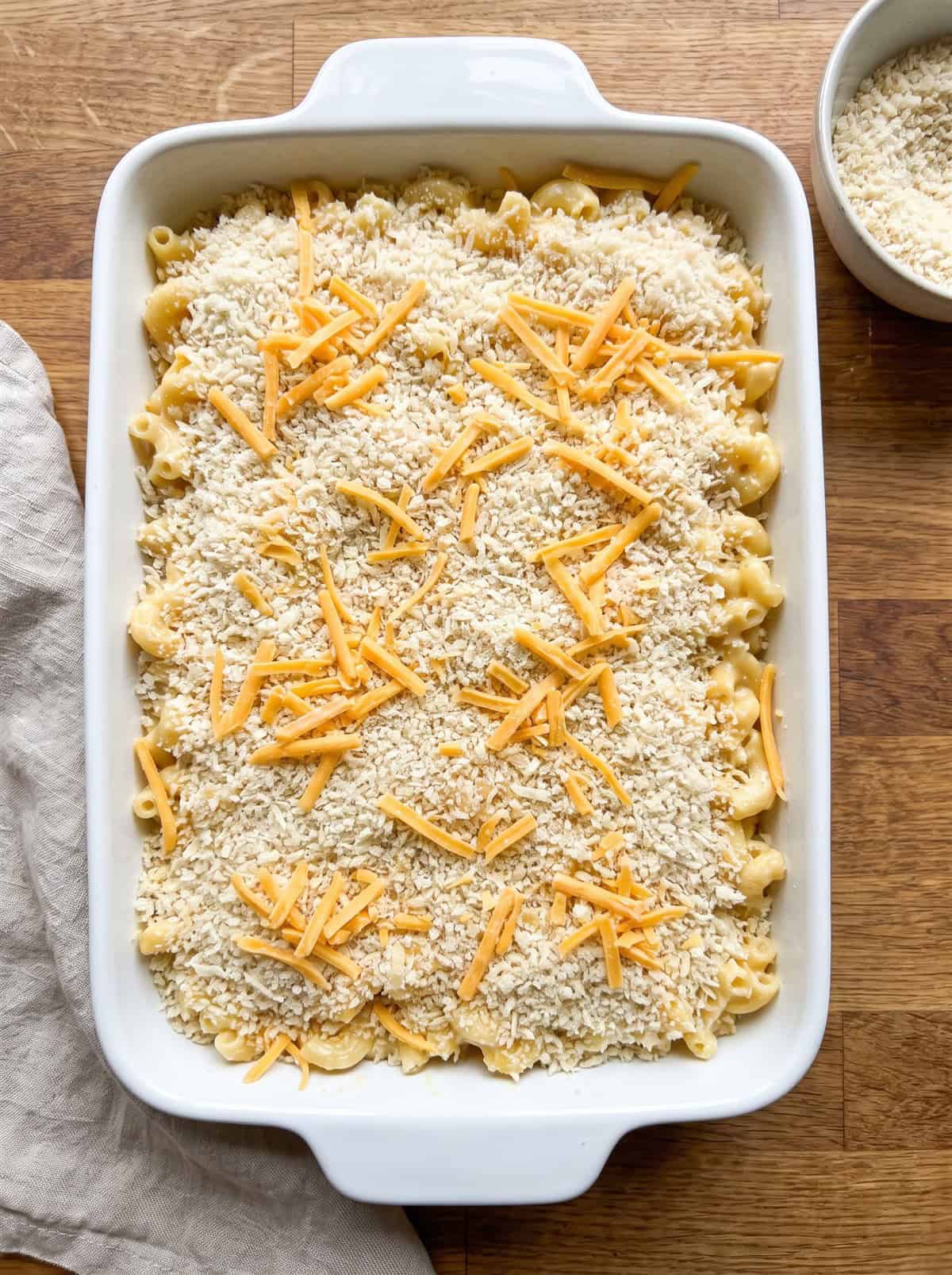 Mac and cheese topped with panko breadcrumbs and shredded cheese ready to bake.