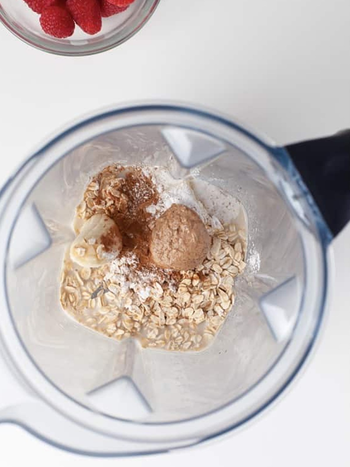 Blending oats, banana, milk, and almond butter in a blender for baked oats.