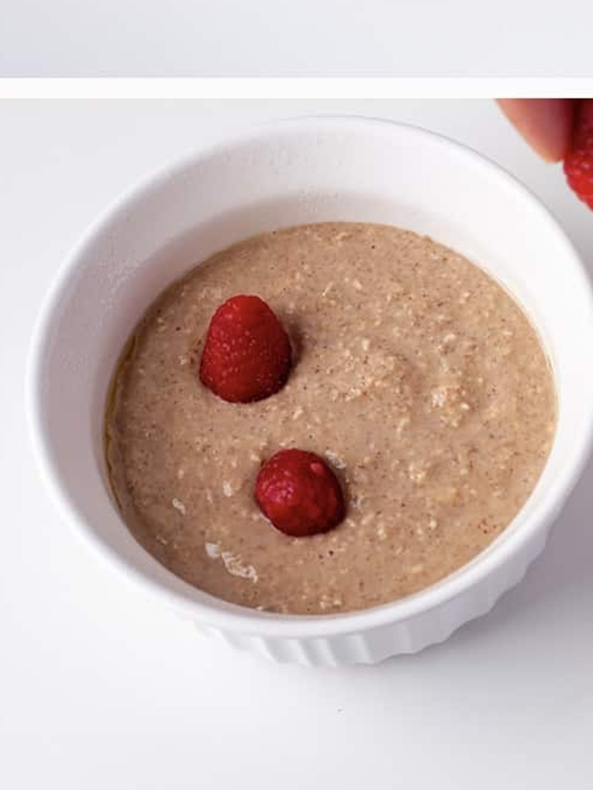 Baked oats batter topped with fresh raspberries ready to bake.