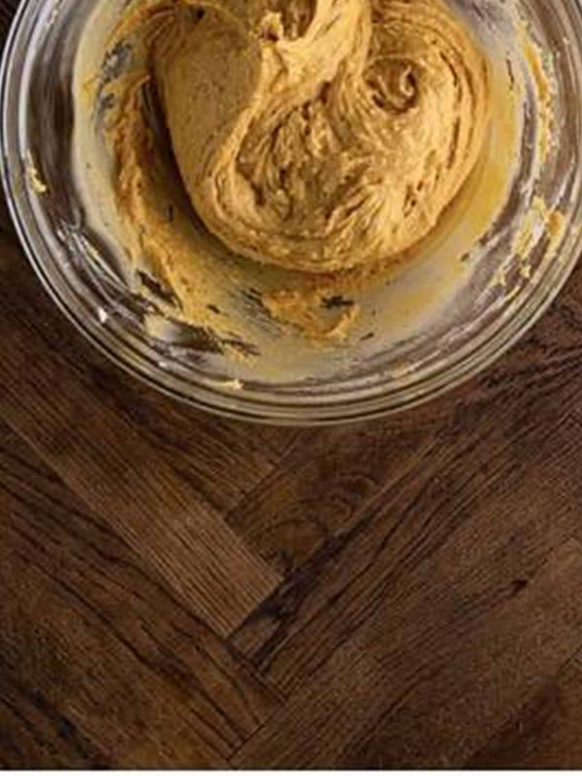 Thick peanut butter donut batter mixed together in a glass bowl.
