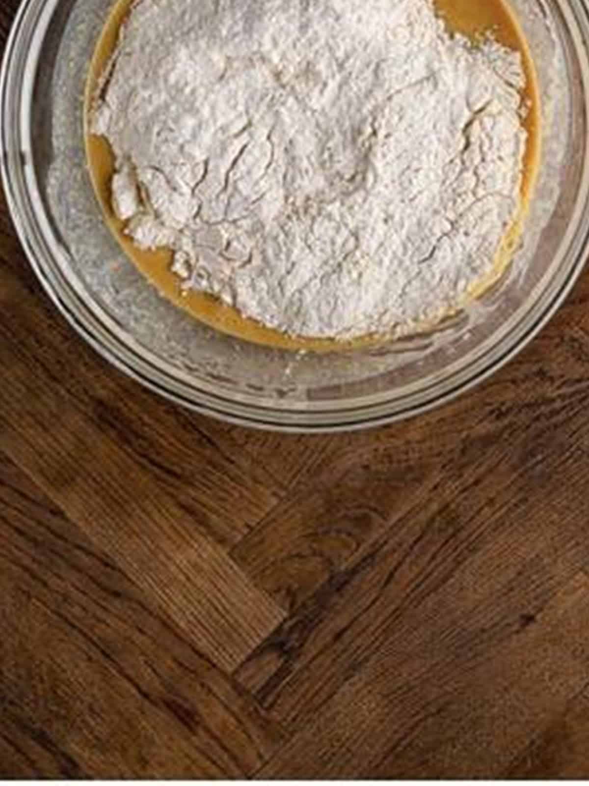Dry ingredients added to the wet peanut butter mixture in a bowl.