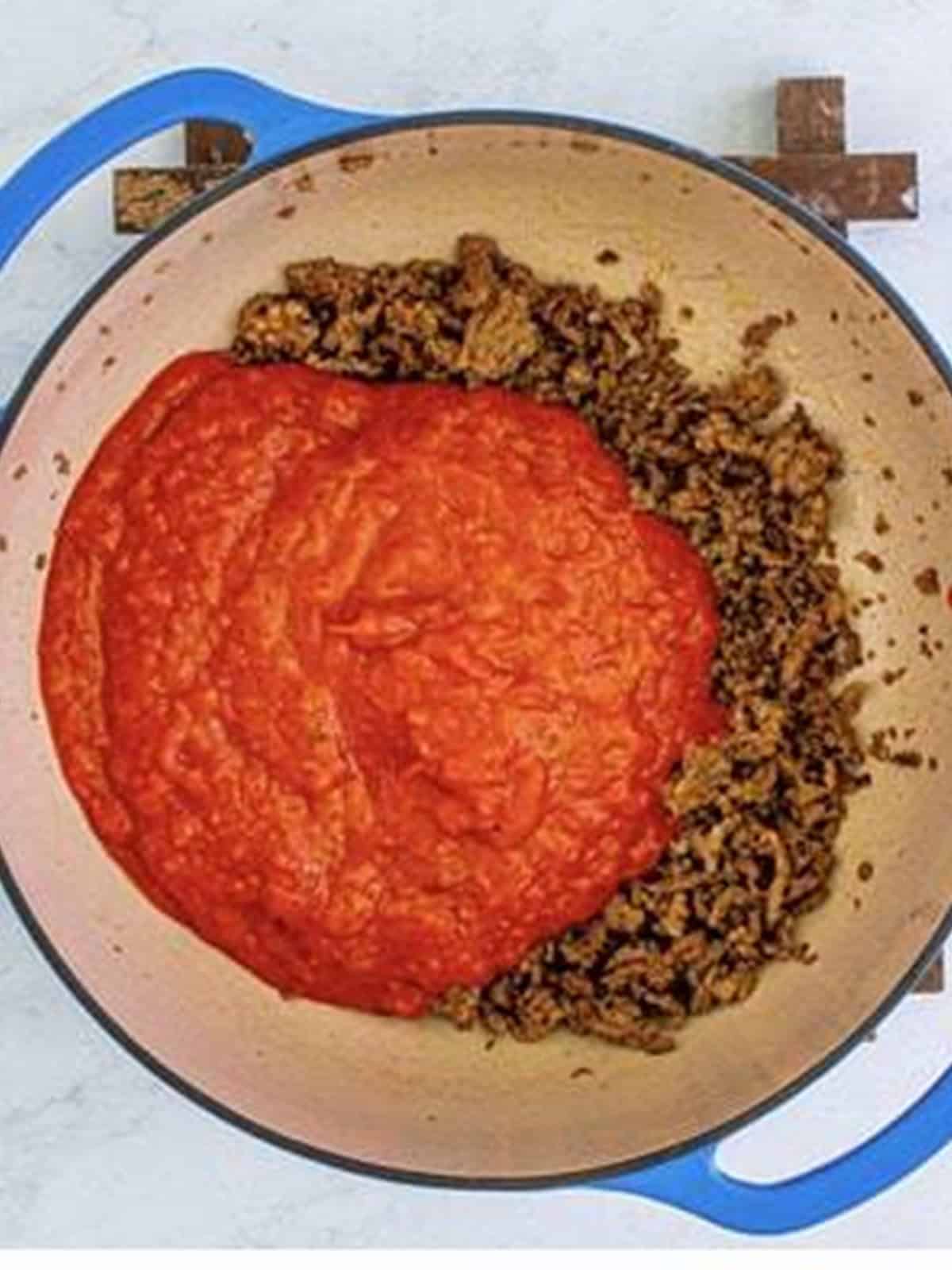 Marinara sauce stirred into the browned meat in a Dutch oven.