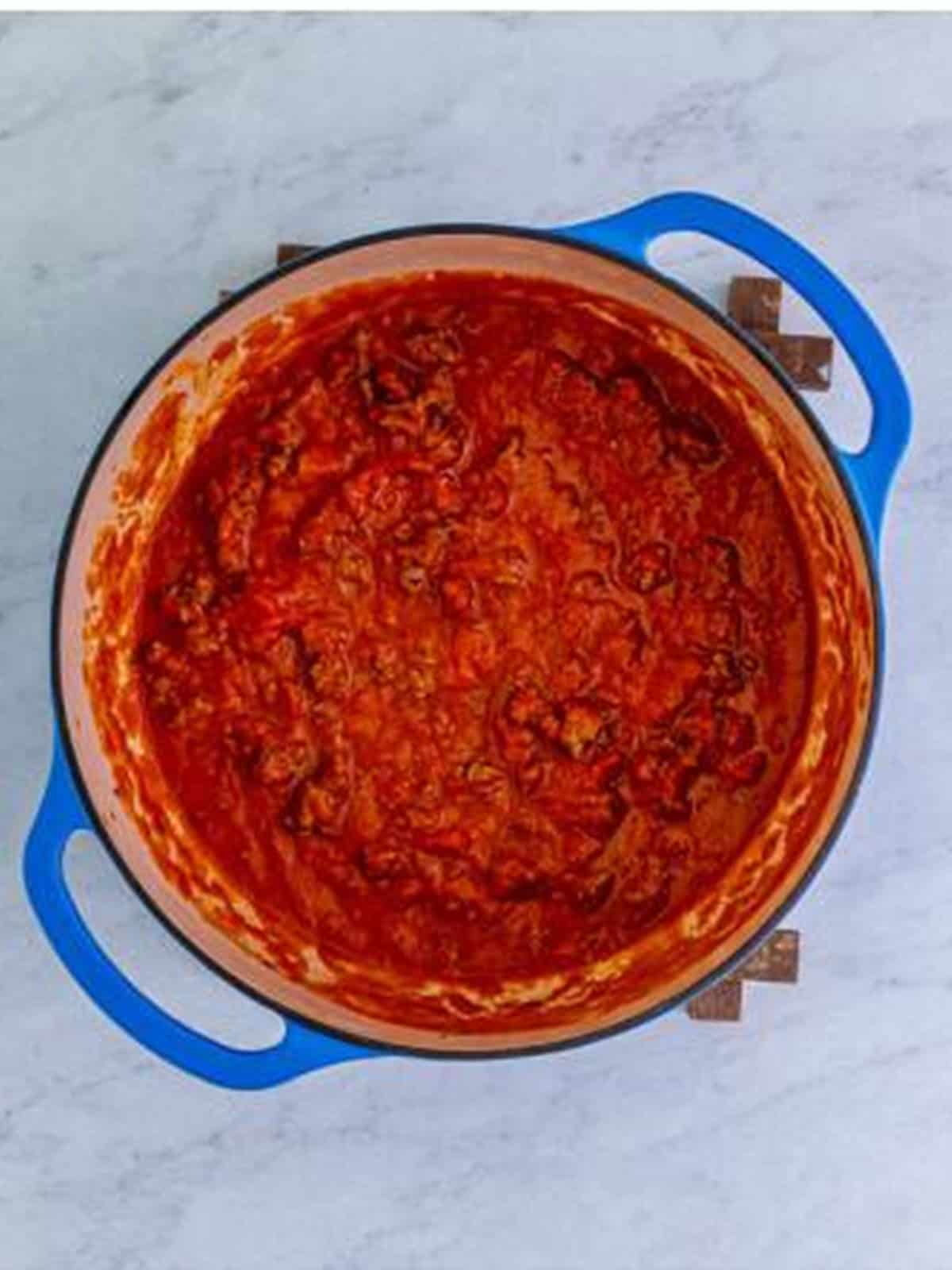 Marinara sauce added to browned beef in a pot