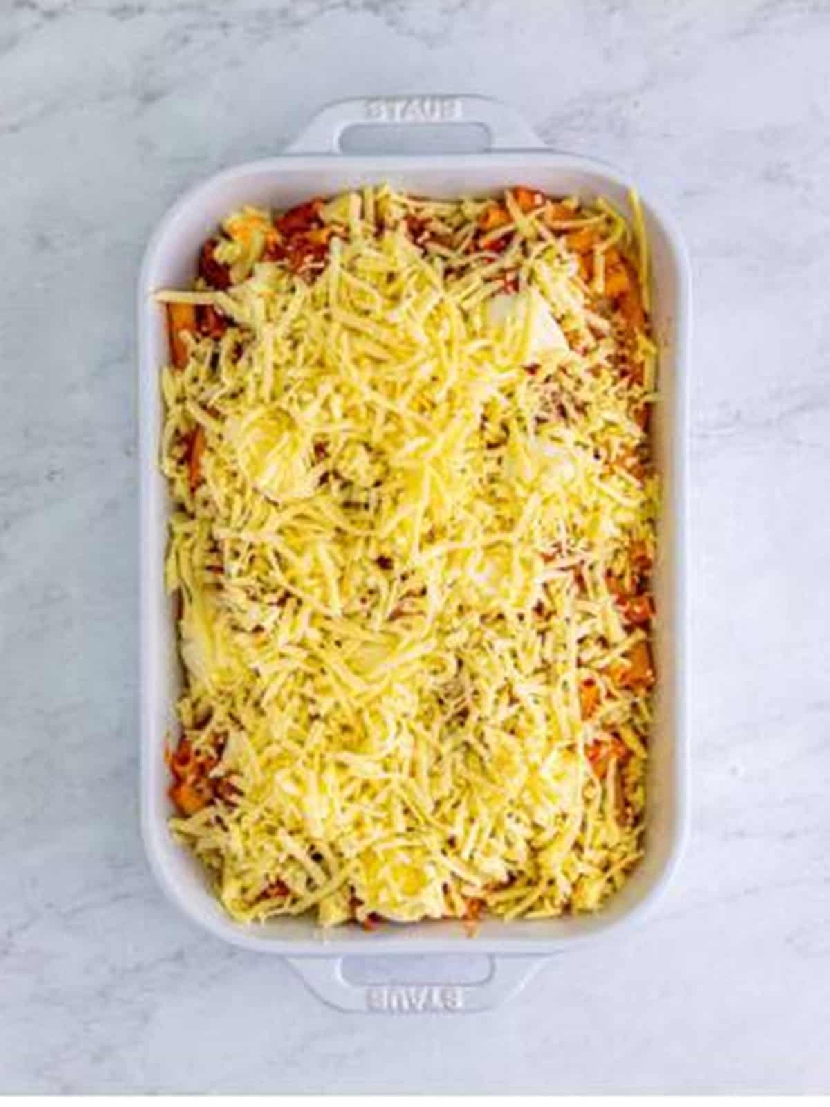 Shredded mozzarella sprinkled over the top of unbaked ziti