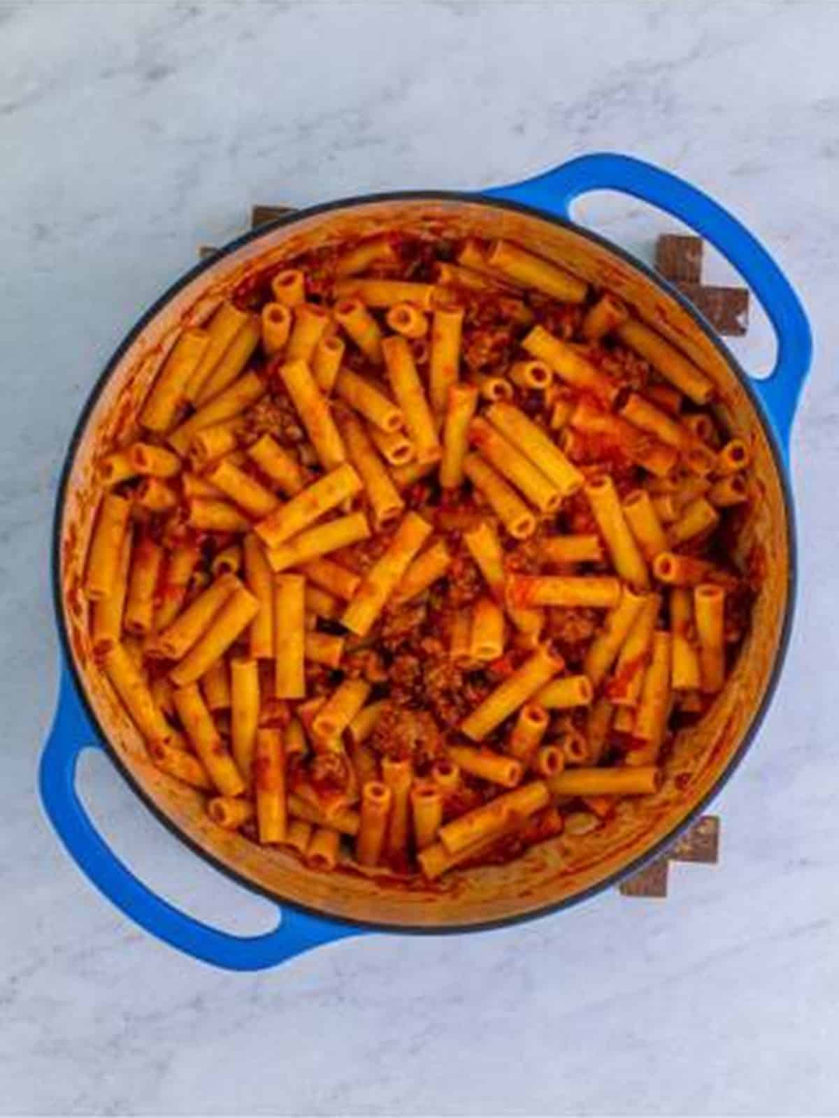 Cooked ziti tossed in meat sauce in a pot