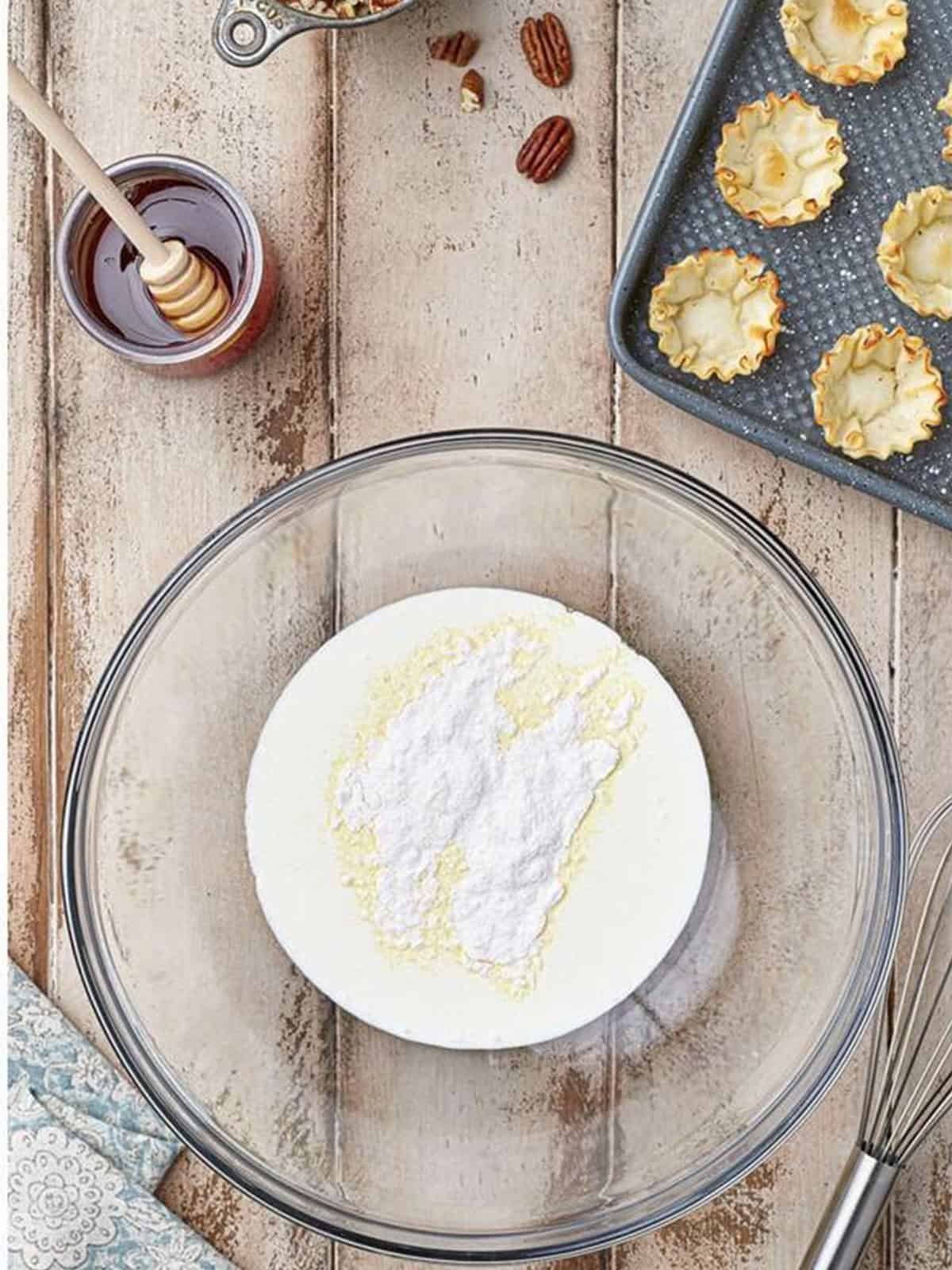 Heavy cream and vanilla pudding powder in a glass bowl to make Baklava Bites filling.