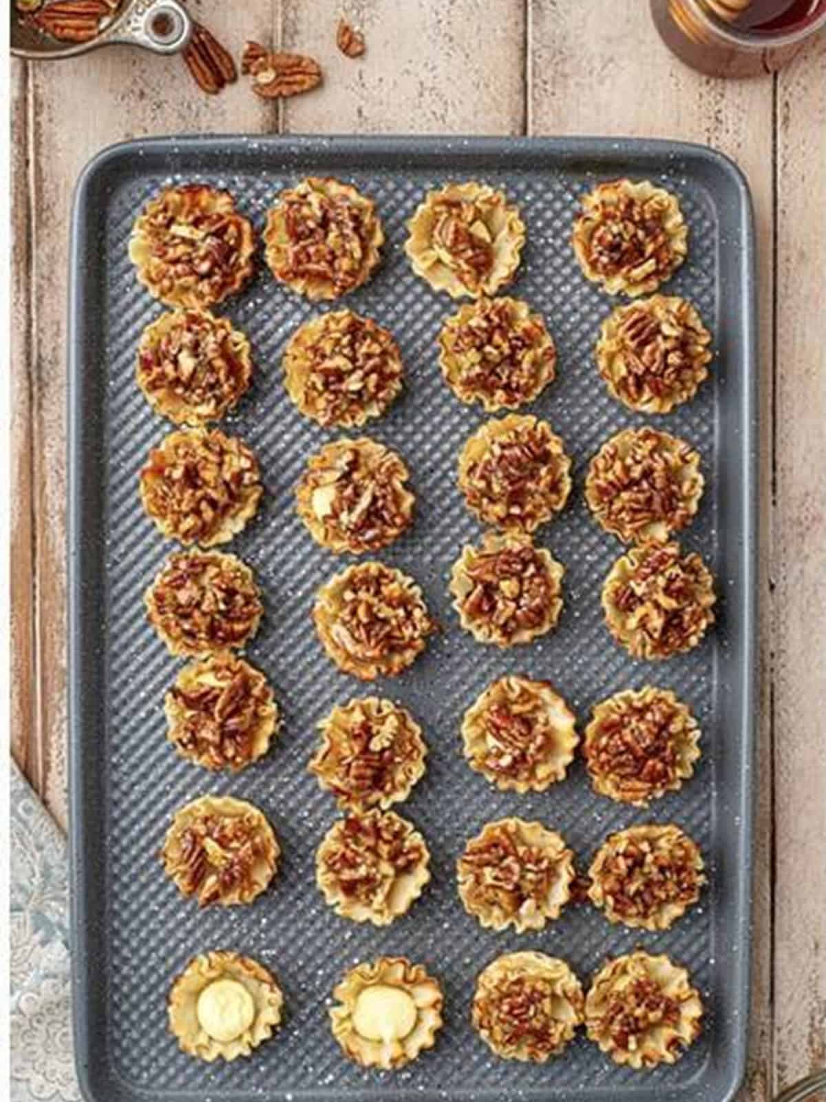 Spooning the honey pecan topping over the filled phyllo cups to finish Baklava Bites.