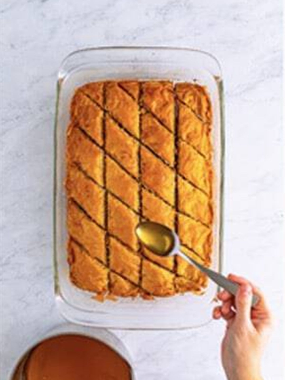 Pouring honey syrup over hot golden baked baklava