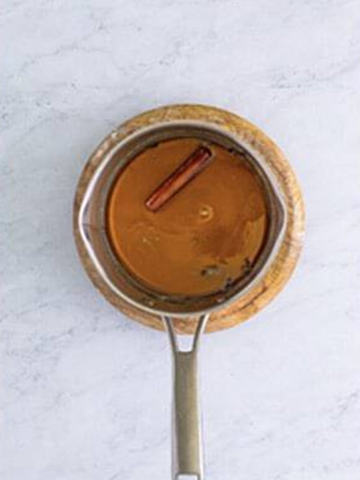 Baklava syrup simmering in a saucepan with a cinnamon stick and cloves