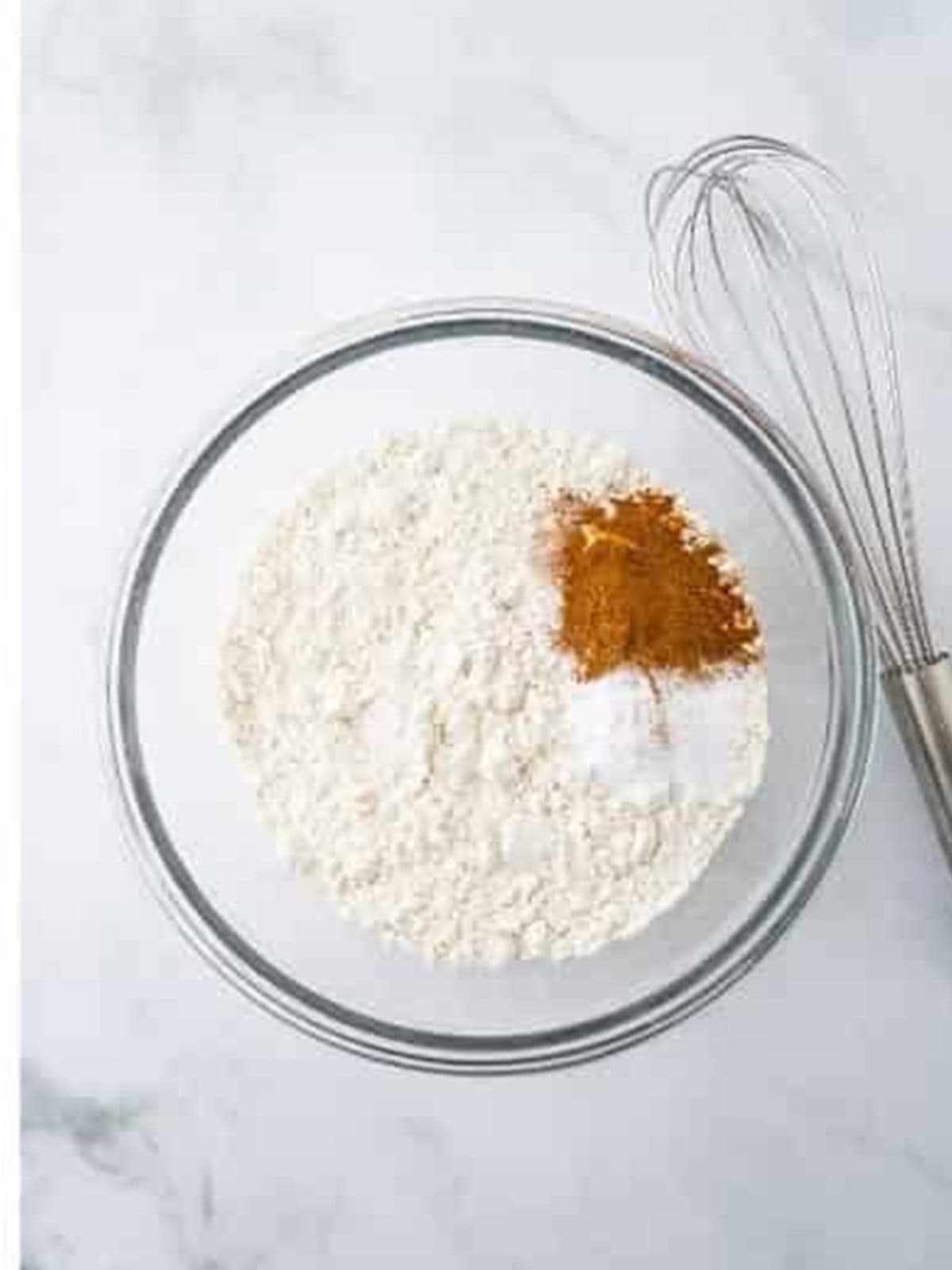 Flour, cinnamon, baking soda, and salt whisked together in a glass bowl.