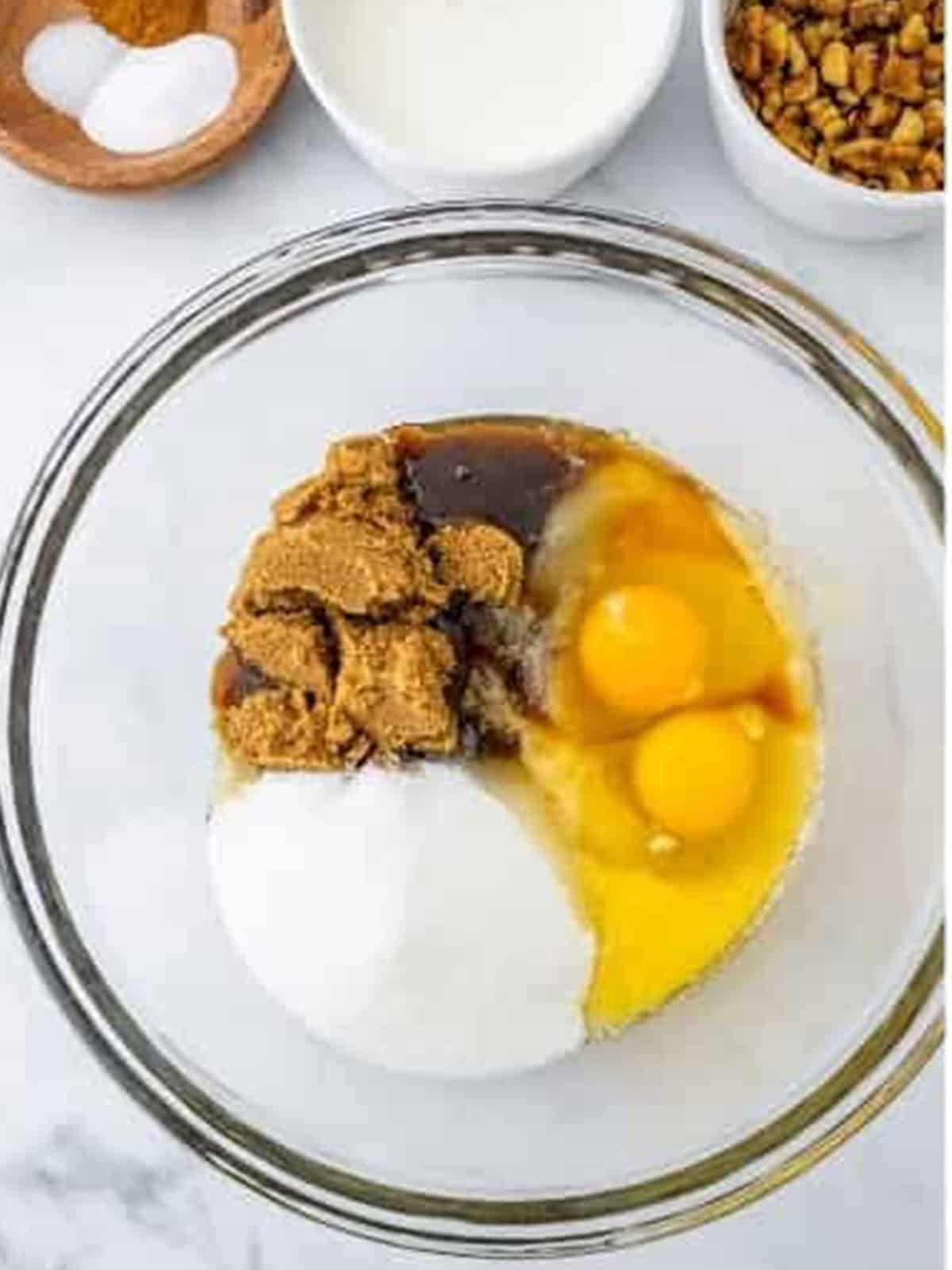 Banana bar wet ingredients with butter, sugars, eggs, and applesauce in a glass bowl.