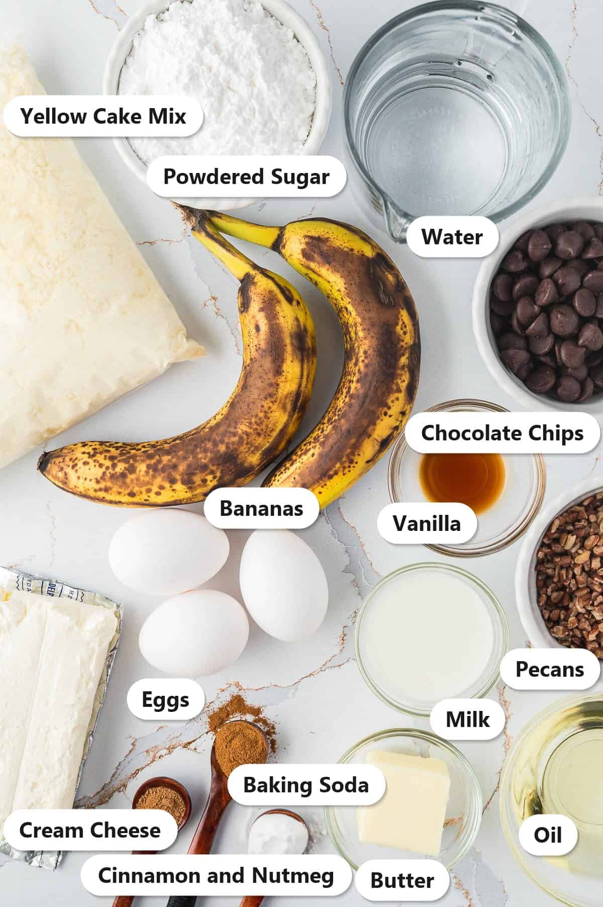 Labeled ingredients for banana bundt cake including yellow cake mix, ripe bananas, chocolate chips, cream cheese, butter, powdered sugar, and spices.