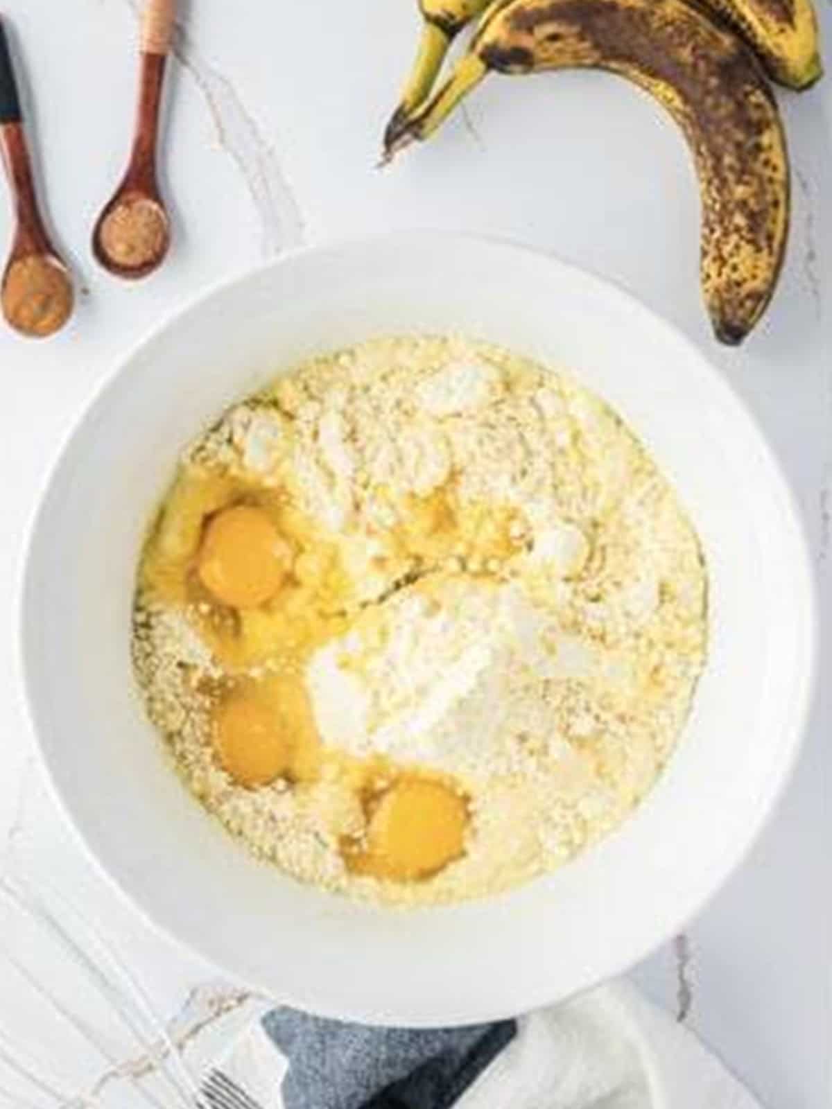 Yellow cake mix and eggs in a large mixing bowl for banana bundt cake.