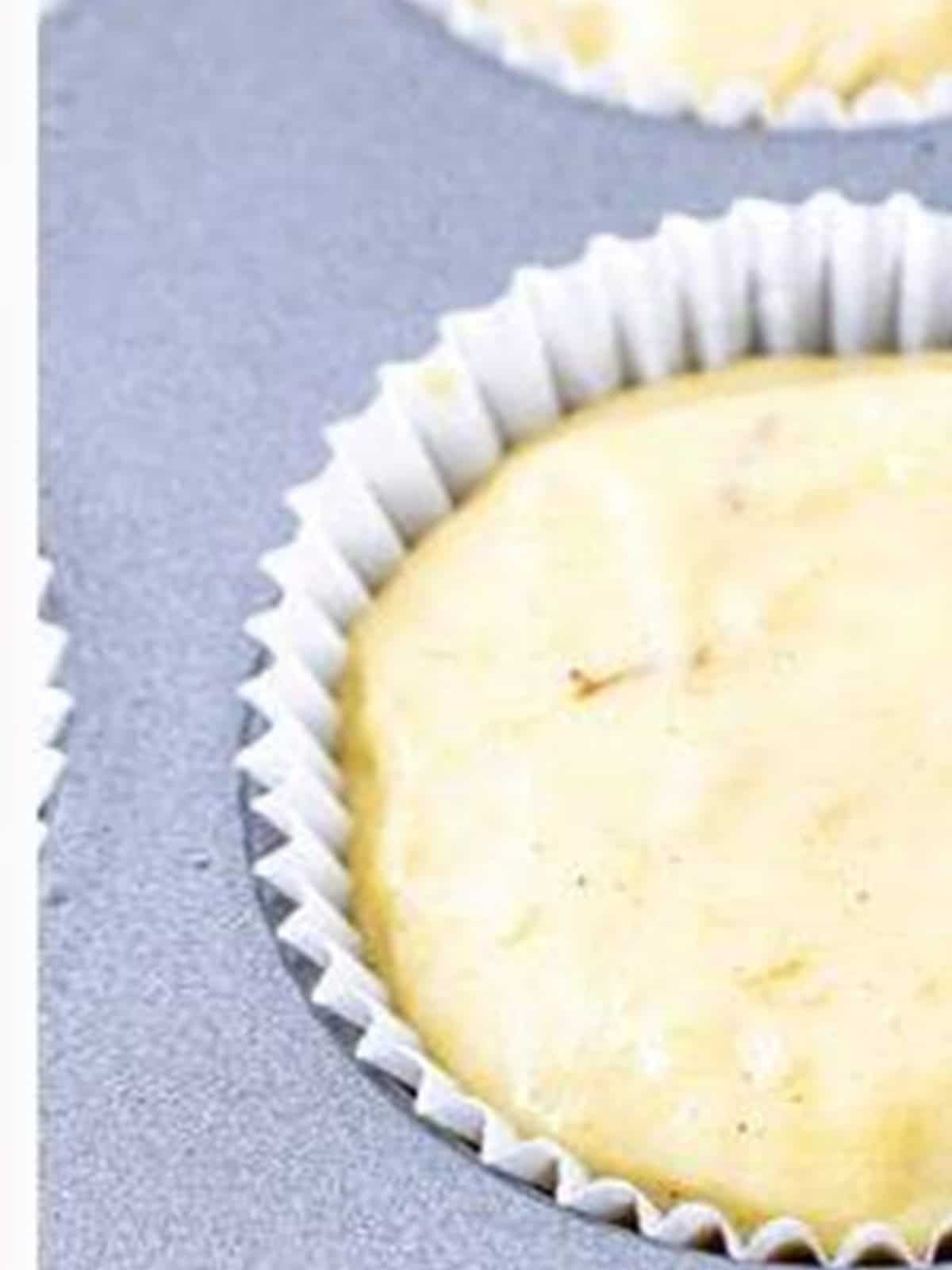 Banana muffin batter spooned into a paper-lined muffin cup.