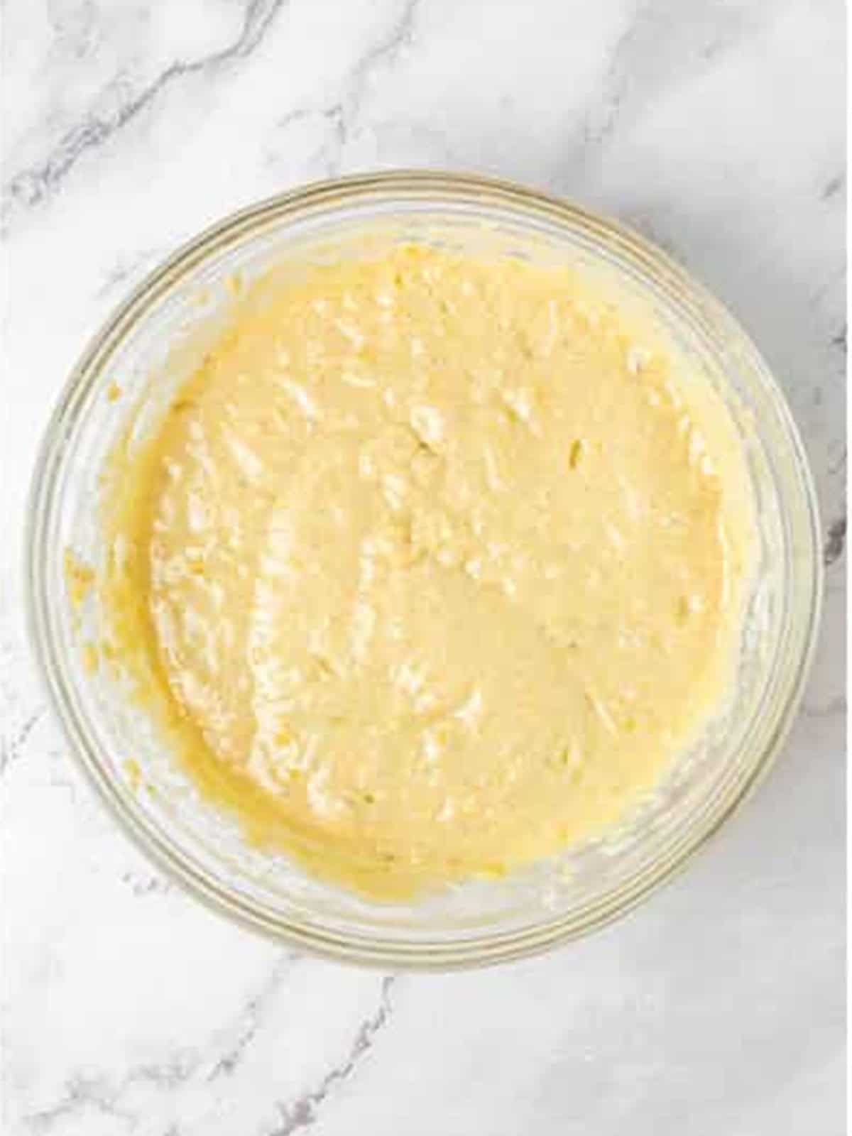 Banana cake batter combined in a glass mixing bowl.