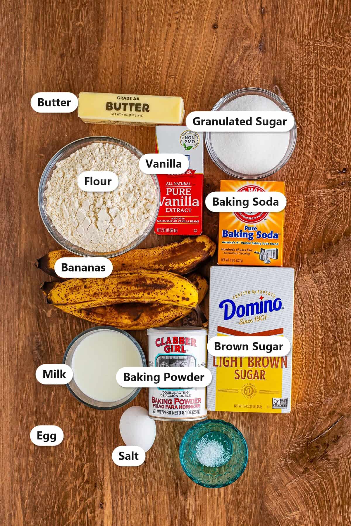 Banana cupcake ingredients labeled including butter, granulated sugar, flour, vanilla, baking soda, bananas, brown sugar, milk, baking powder, egg, and salt.