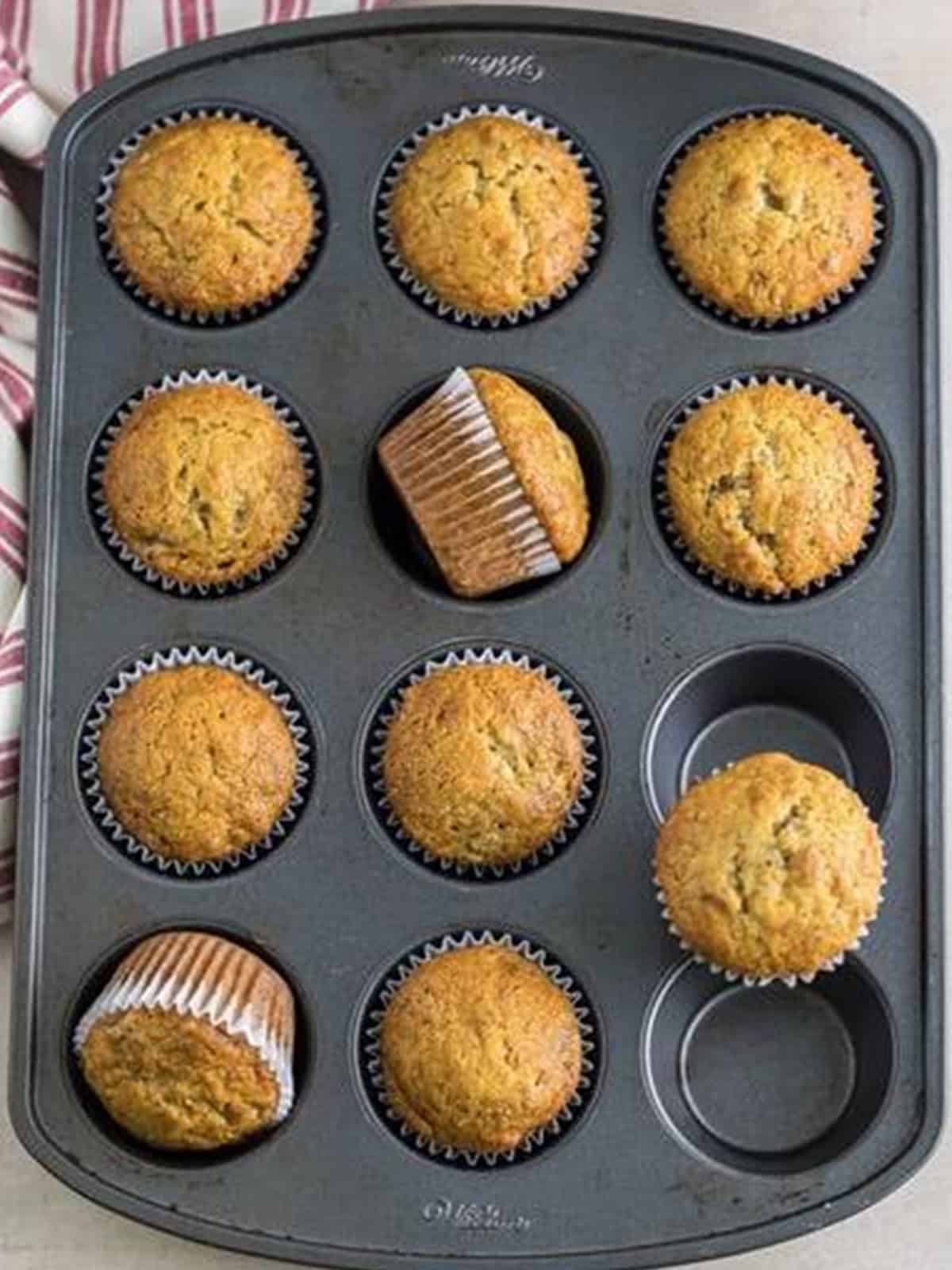 Baked banana cupcakes cooling in the muffin tin, golden and domed.