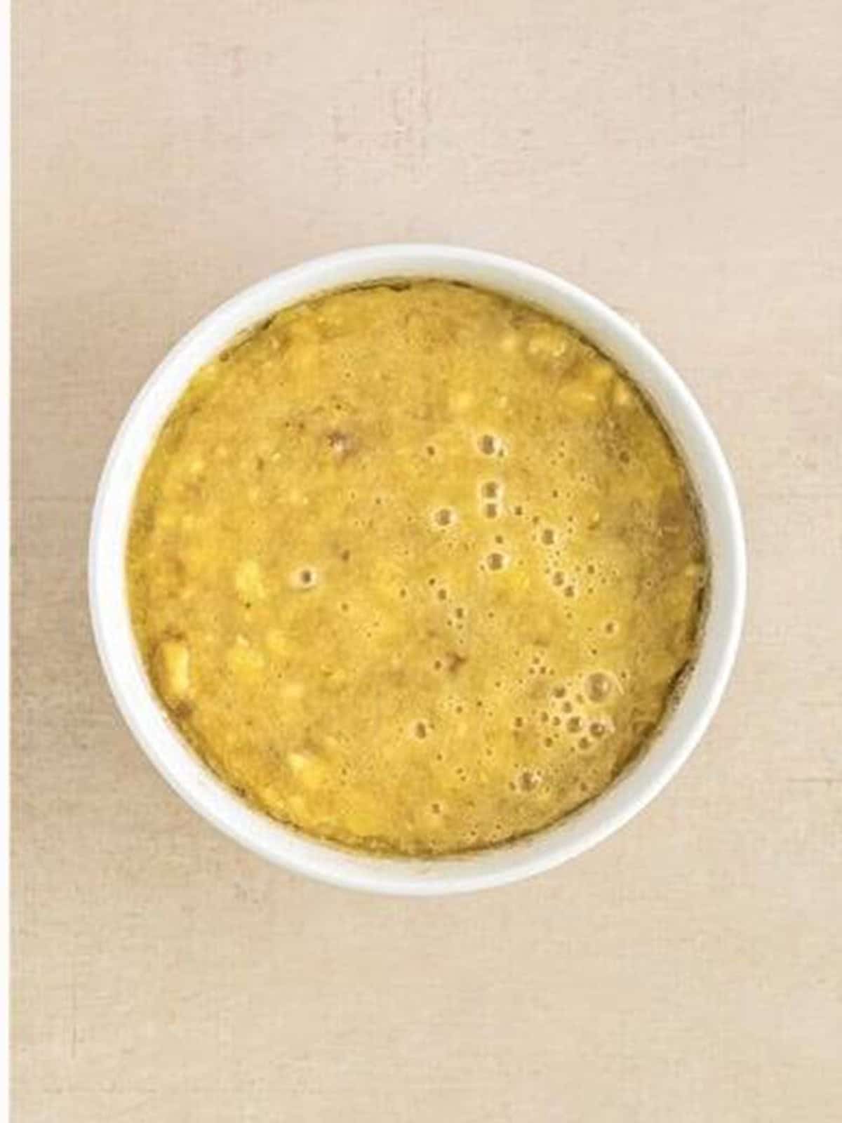 The wet banana mixture whisked smooth in a white bowl.