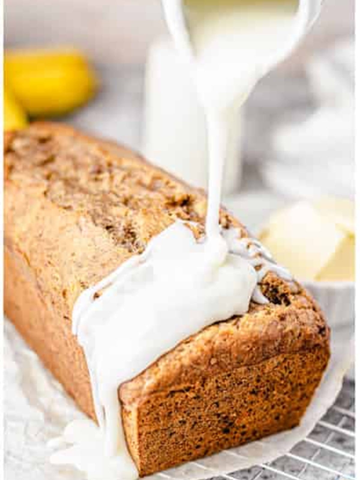 Vanilla glaze being poured over the cooled banana nut bread loaf.