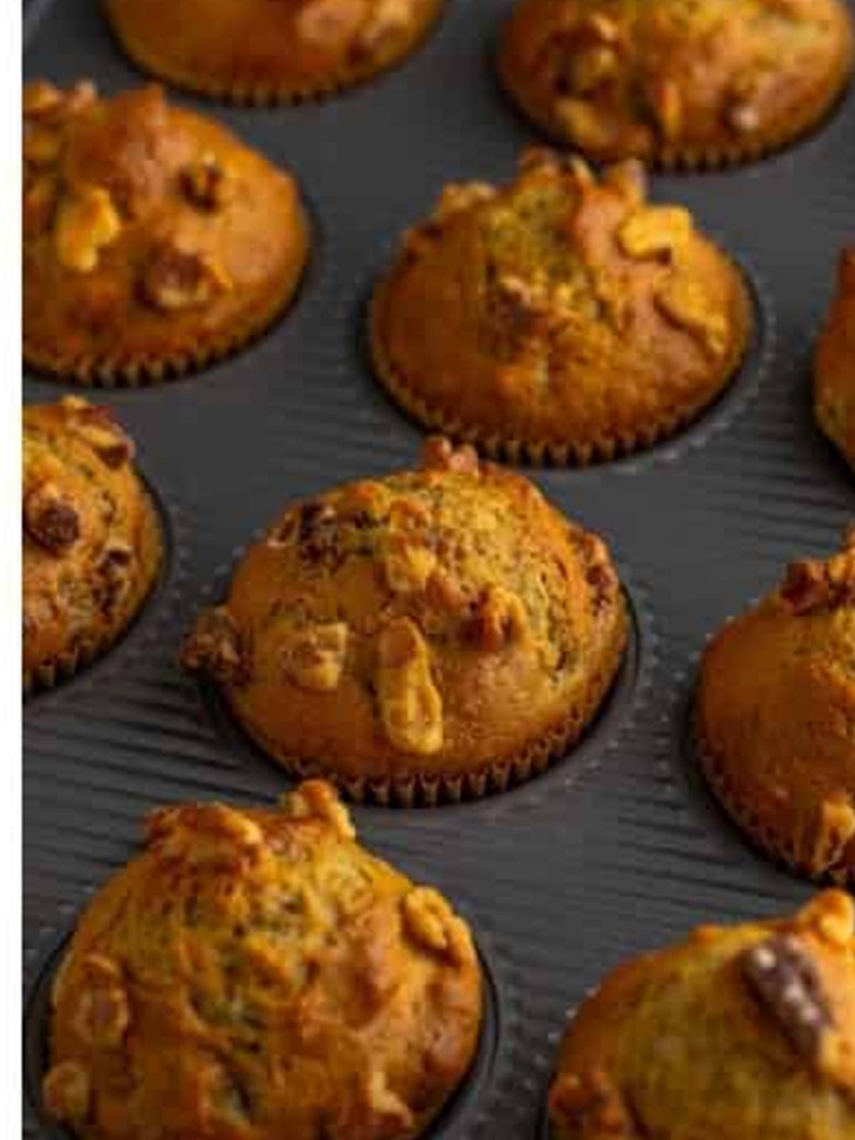 Golden baked banana nut muffins in a muffin tin.