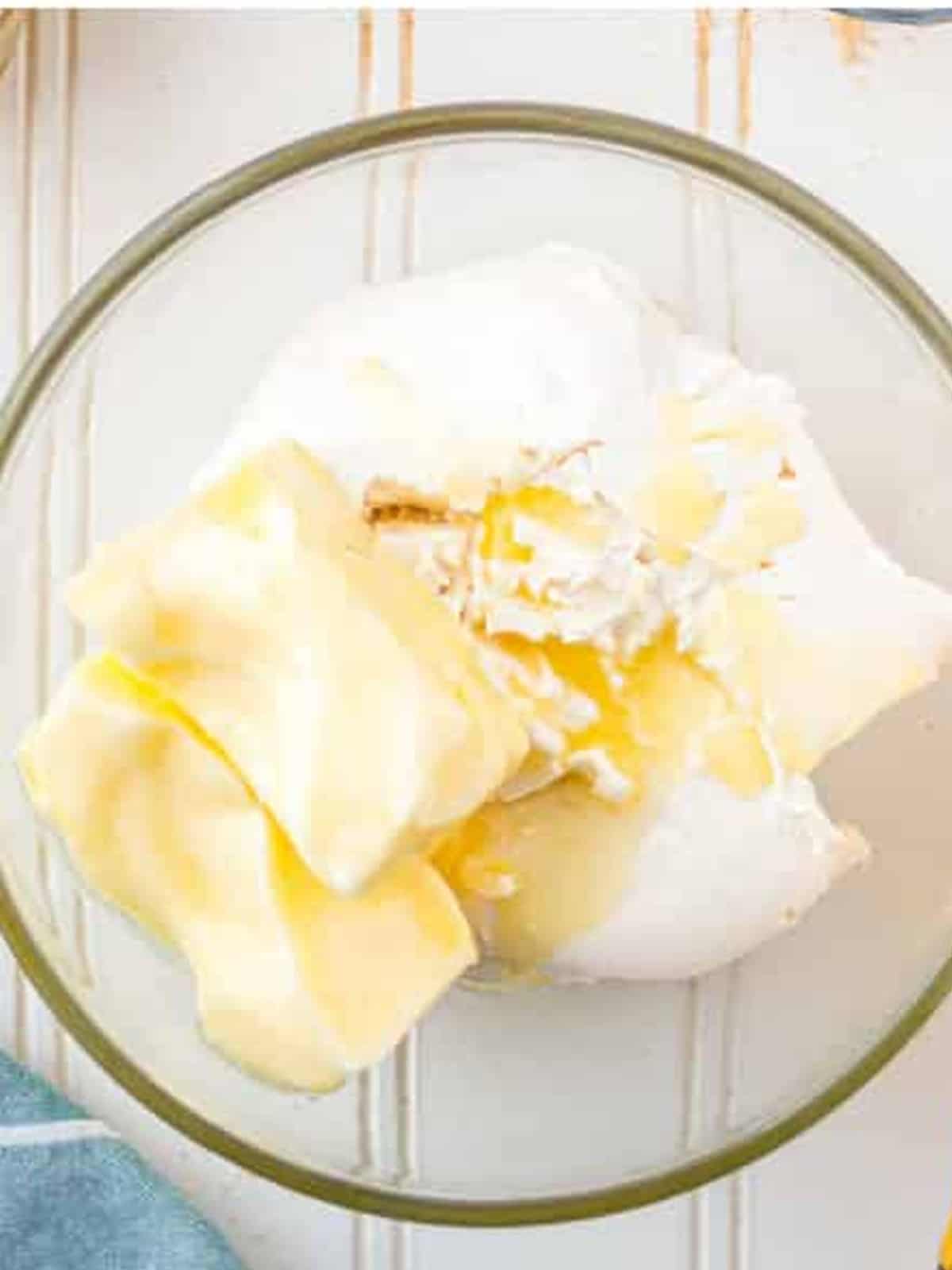 Cream cheese and butter in a glass mixing bowl ready to be beaten.
