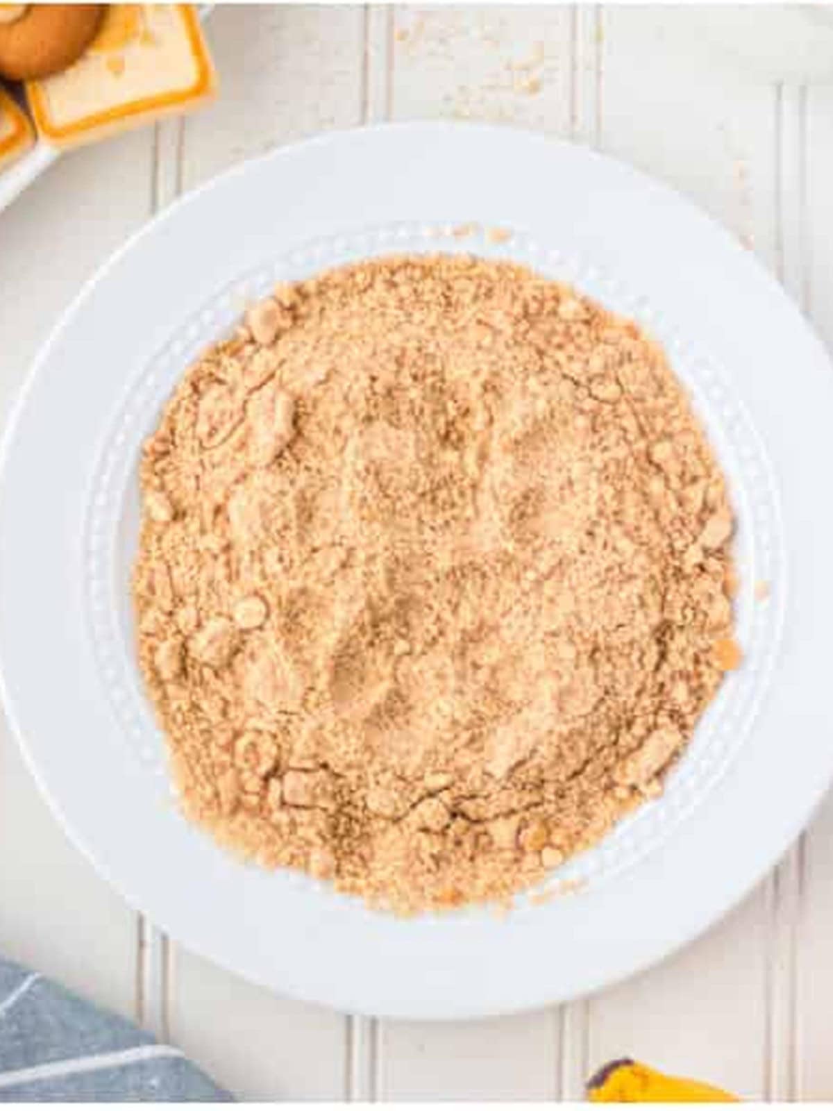 Crushed vanilla wafer crumbs spread on a plate for coating.
