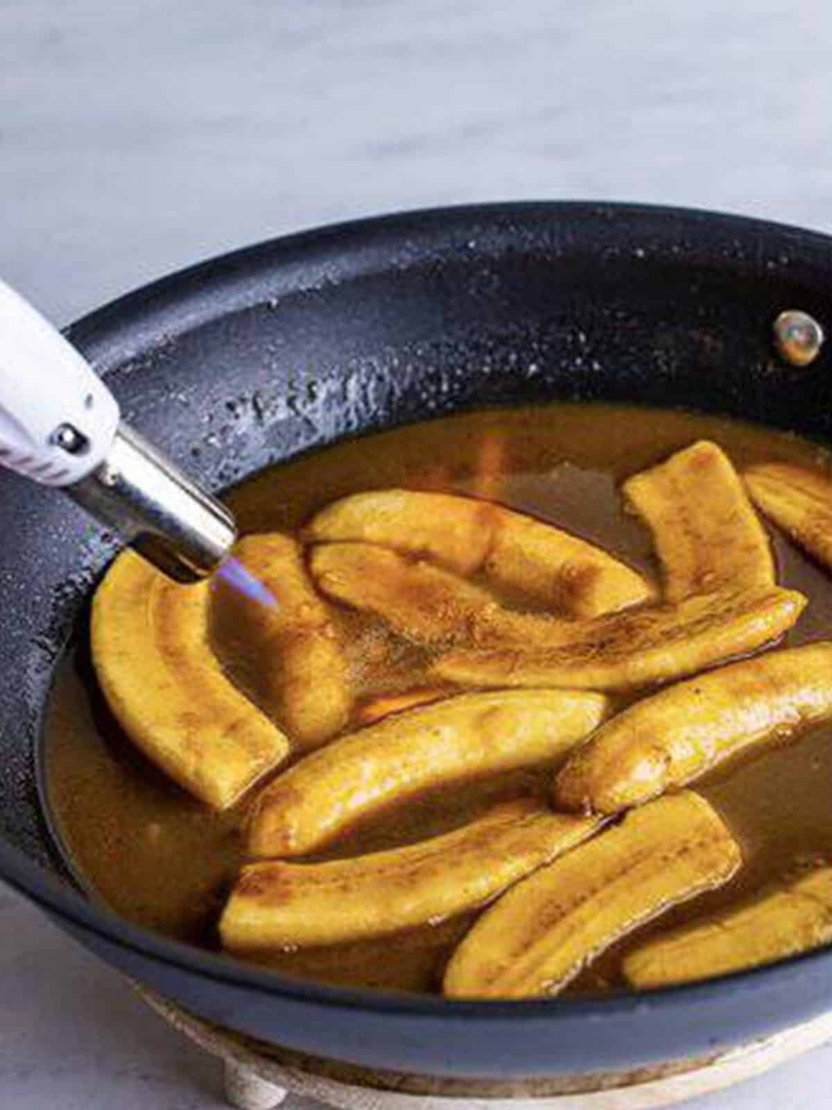 Flambeing the rum in the bananas foster skillet with a torch.