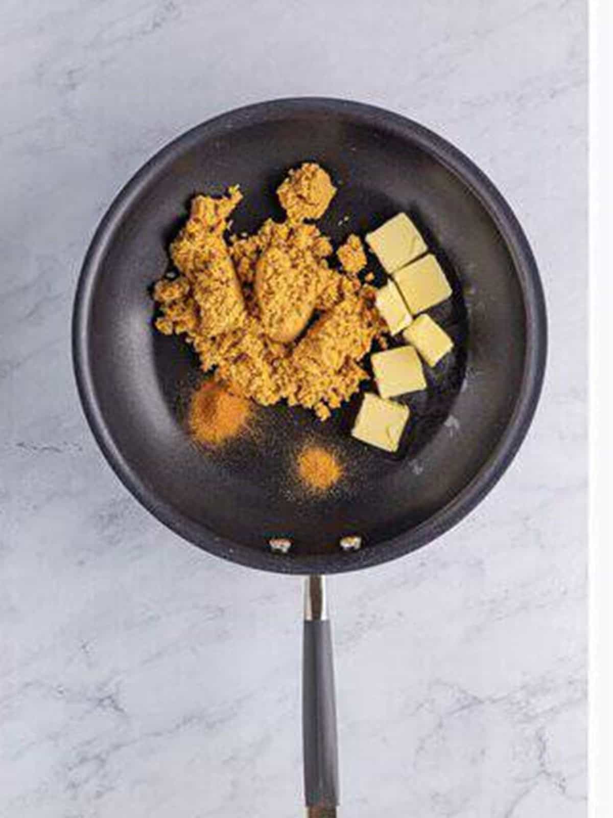Butter, brown sugar, and spices melting in a skillet for bananas foster sauce.