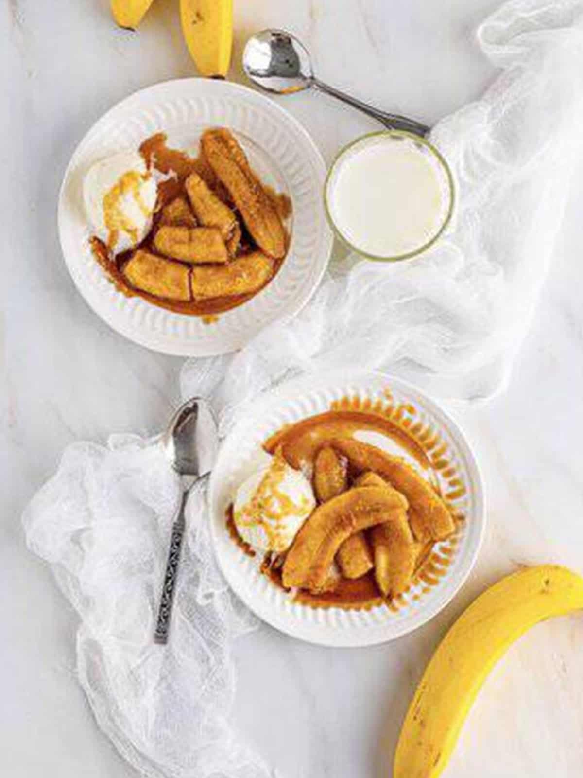 Bananas foster served over vanilla ice cream on a white plate.