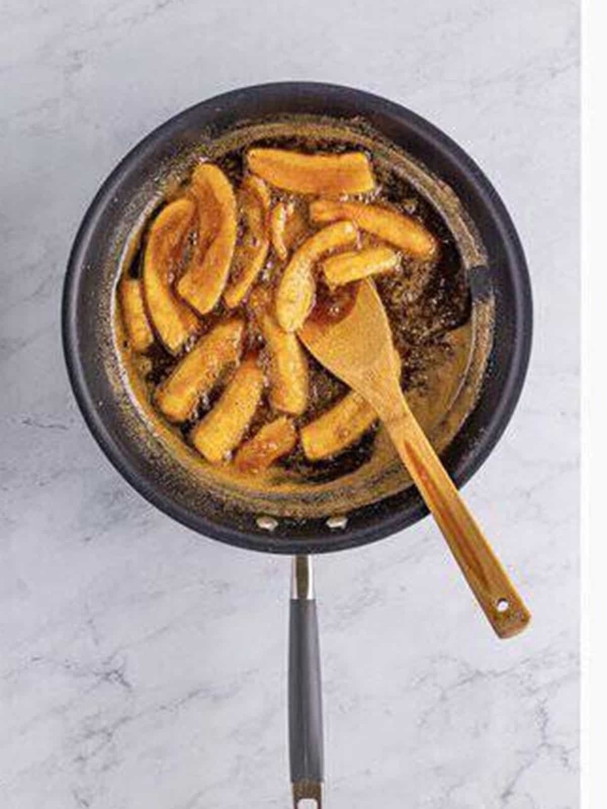 Bananas foster simmering in a thickened caramel rum sauce.