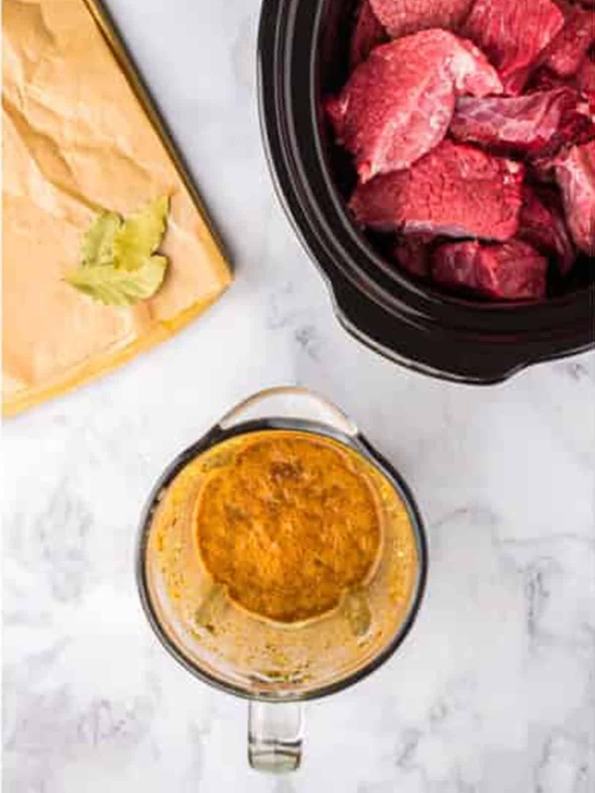 Beef chuck chunks added to a slow cooker with chipotle adobo sauce and beef broth for barbacoa.