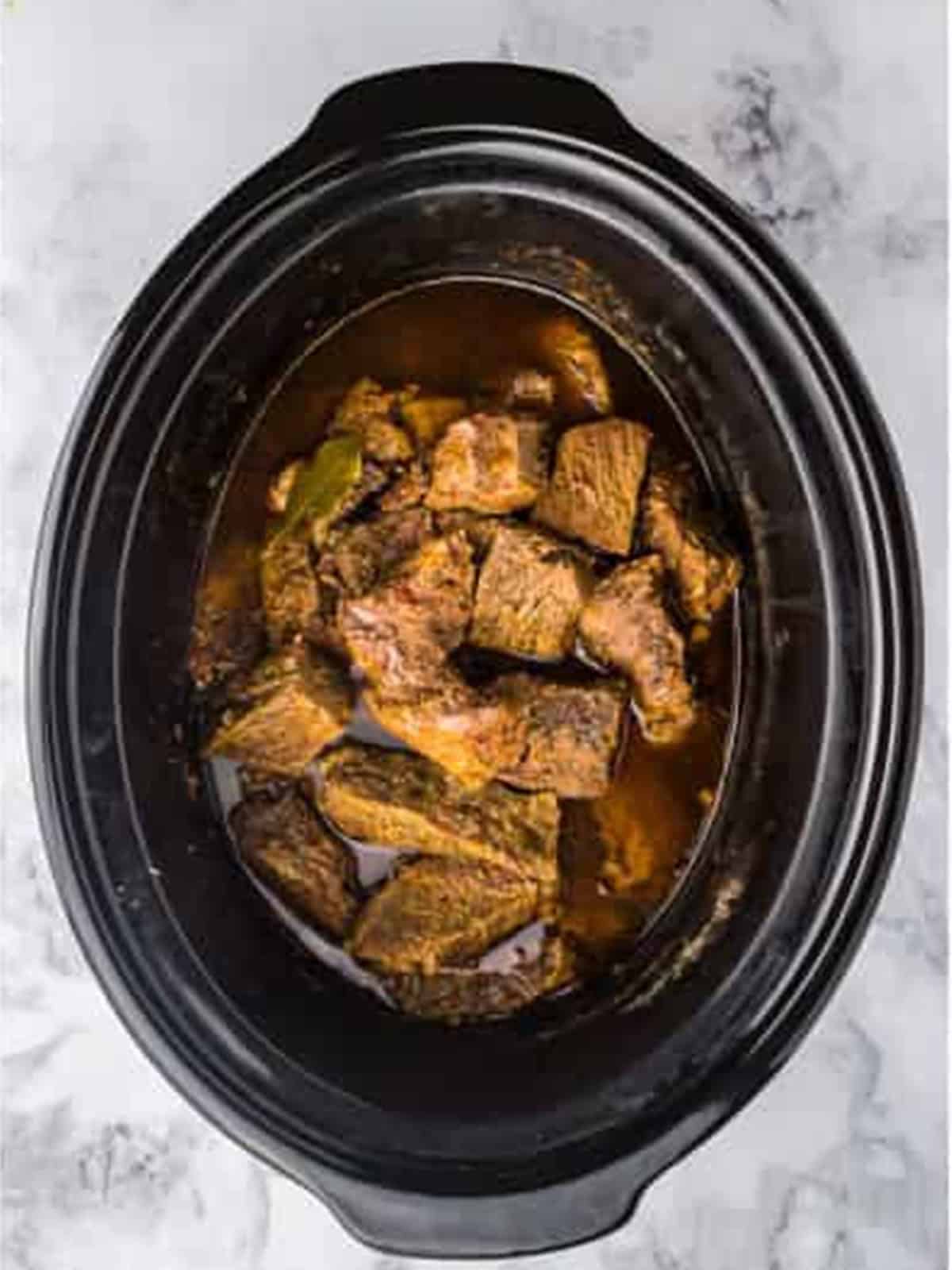 Tender cooked beef chunks in the slow cooker for barbacoa.