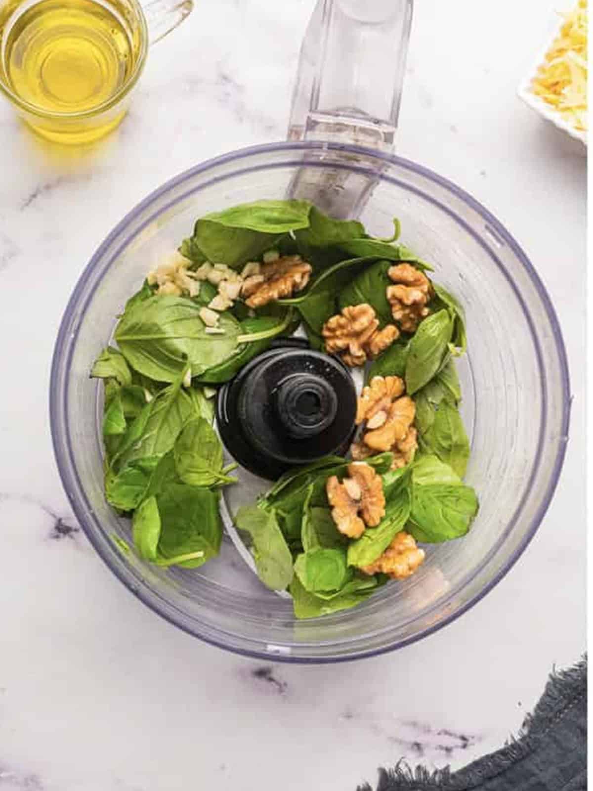 Fresh basil, toasted walnuts, and garlic in a food processor to make pesto sauce.