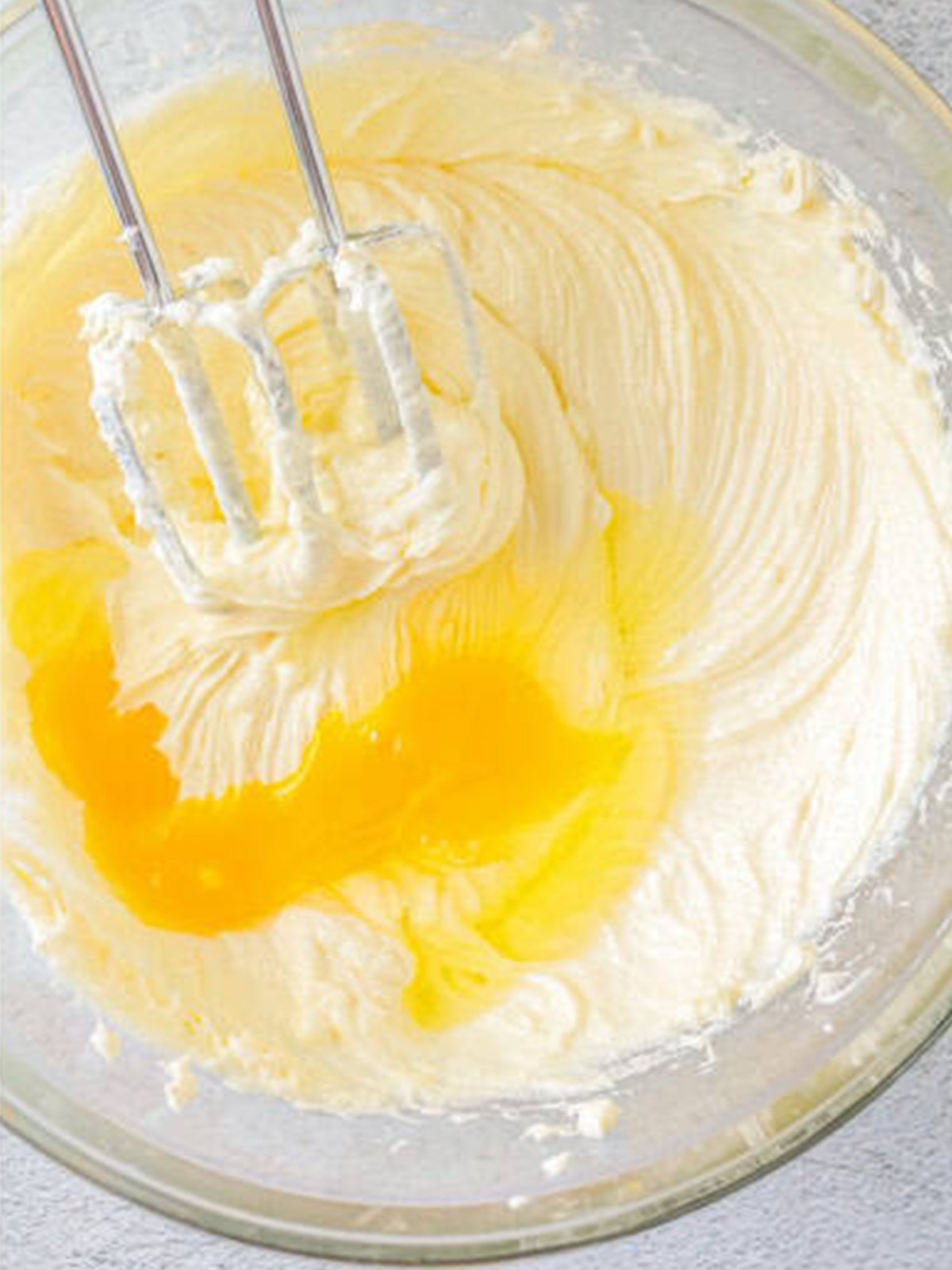 Eggs added one at a time to the cream cheese batter for basque cheesecake.