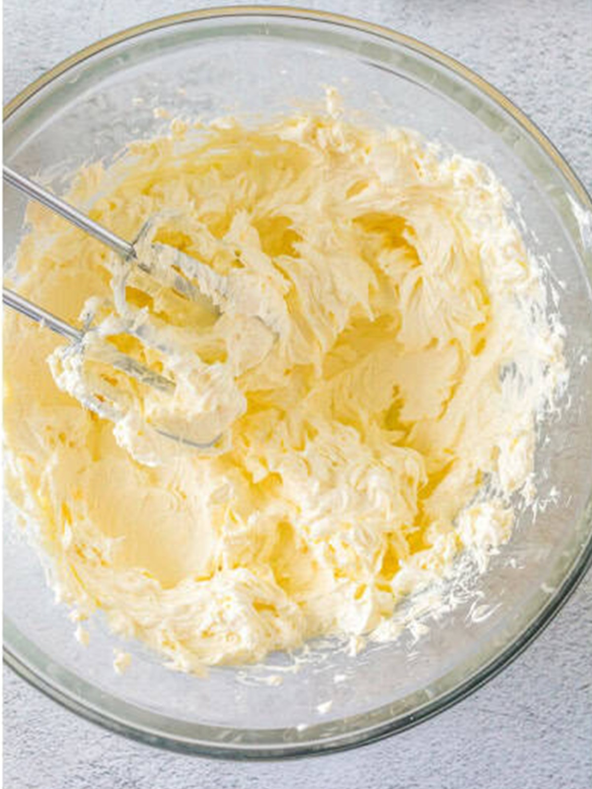 Cream cheese, sugar, and salt creamed together in a mixing bowl for basque cheesecake.