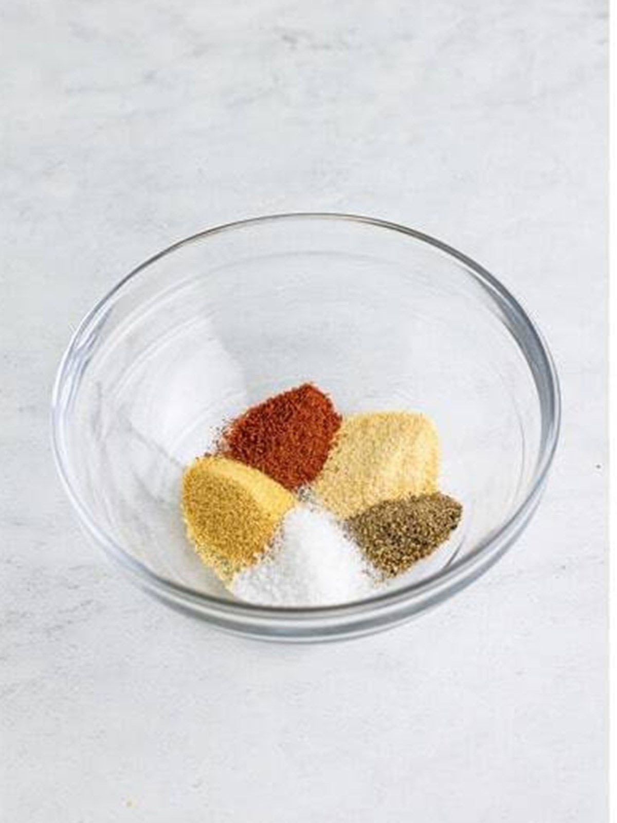 Salt, pepper, garlic powder, onion powder, and paprika stirred together in a small bowl.