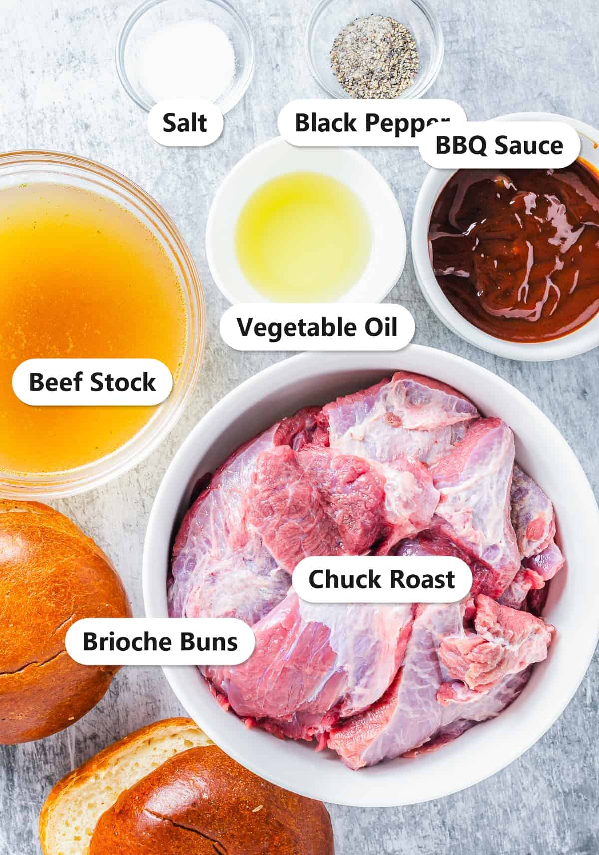Labeled ingredients for slow cooker BBQ beef sandwiches including chuck roast, beef stock, BBQ sauce, oil, salt, pepper, and brioche buns.