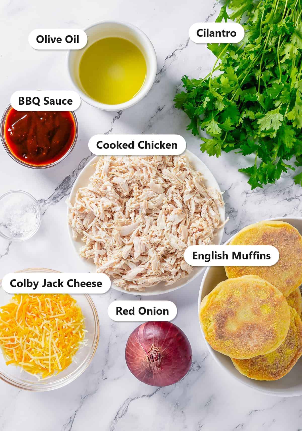 Labeled ingredients for BBQ chicken English muffin pizza including English muffins, cooked chicken, BBQ sauce, Colby Jack cheese, red onion, olive oil, and cilantro.