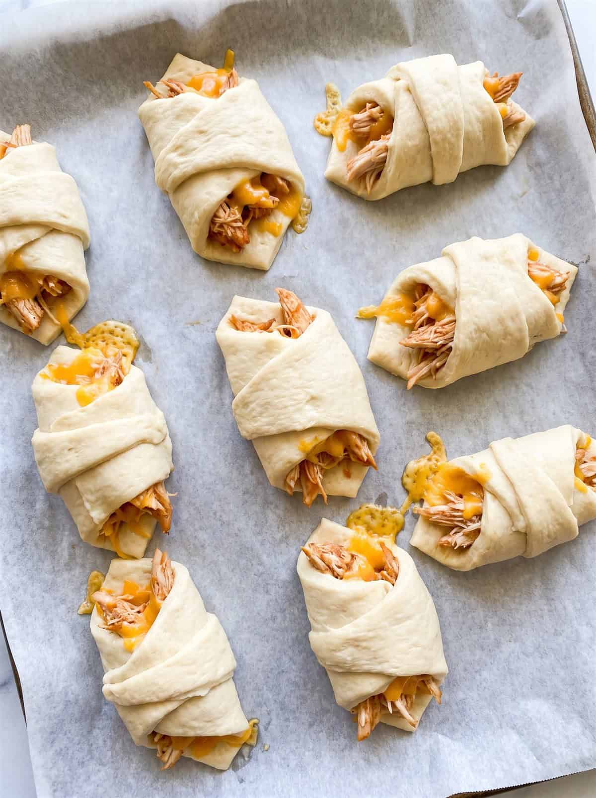 Unbaked BBQ chicken crescent rolls on a baking sheet.