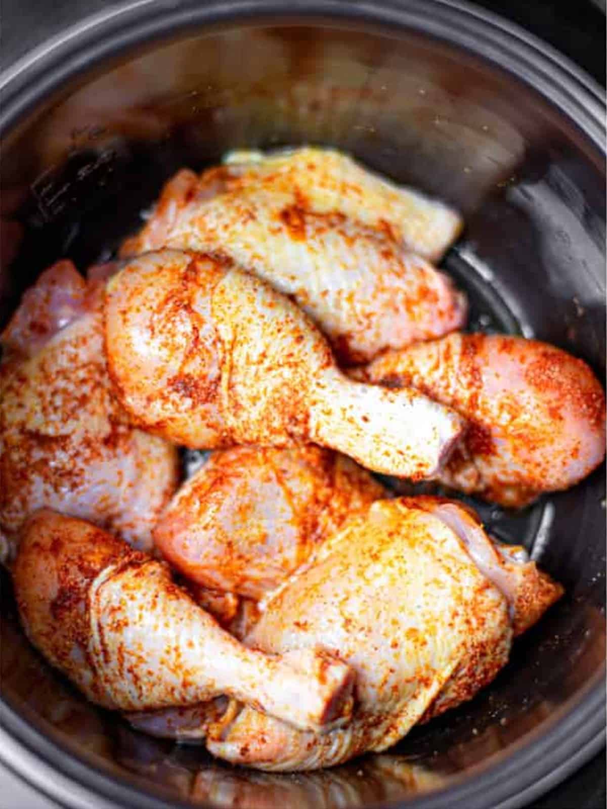 Chicken pieces seasoned with spice rub in the slow cooker.