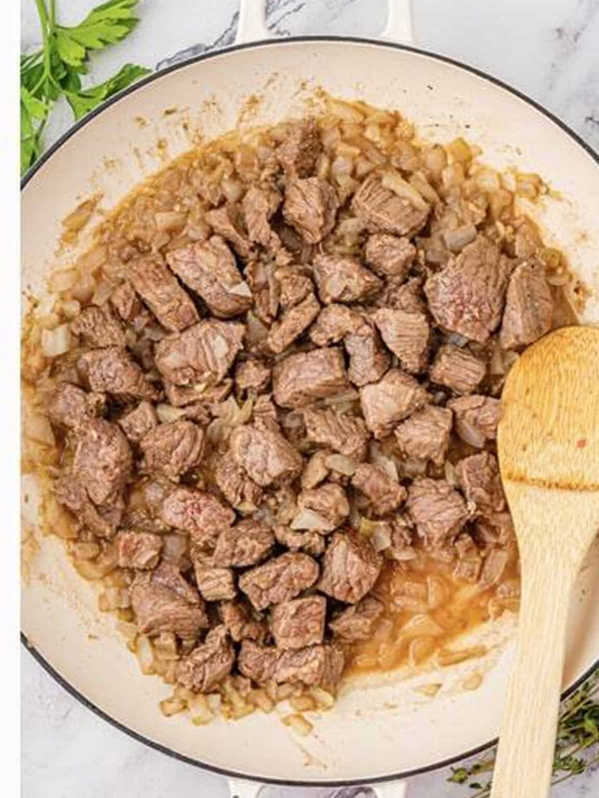Beef stew meat browned in a skillet for beef barley soup.