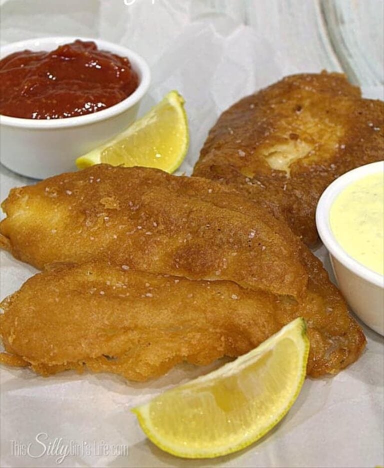 Beer batter for fish fried golden brown served with ketchup, tartar sauce, and lemon wedges.
