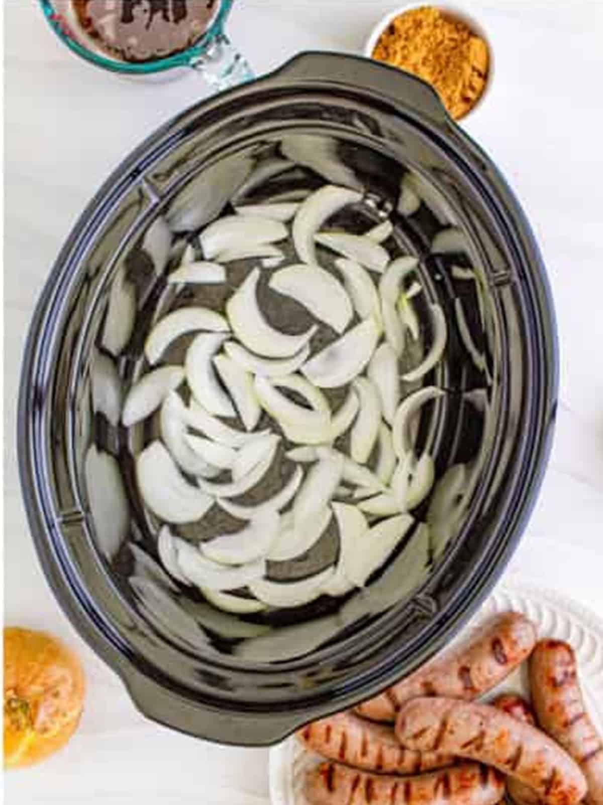 Sliced onions and brown sugar layered in the bottom of a slow cooker.