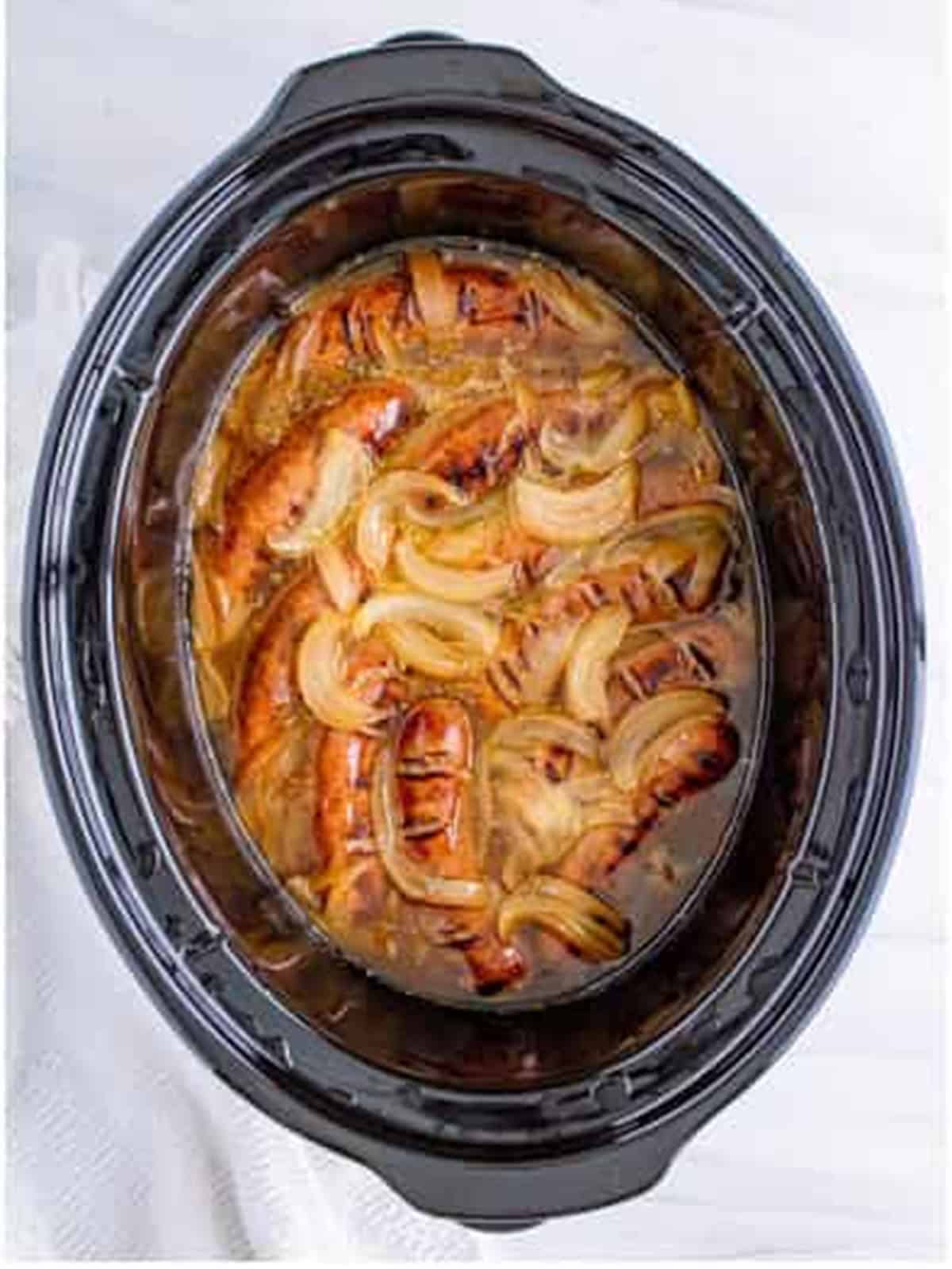 Tender slow cooked beer brats with caramelized onions ready to serve.