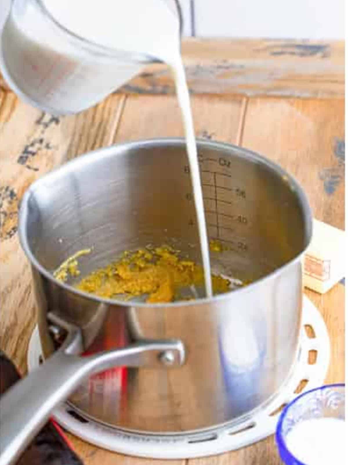 Milk being whisked into the roux in a saucepan to make beer cheese.