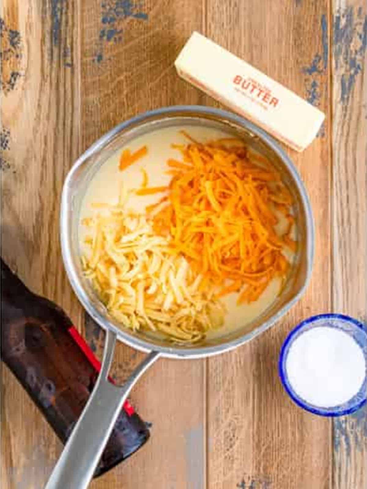 Shredded cheddar and gouda cheese added to the saucepan for beer cheese.